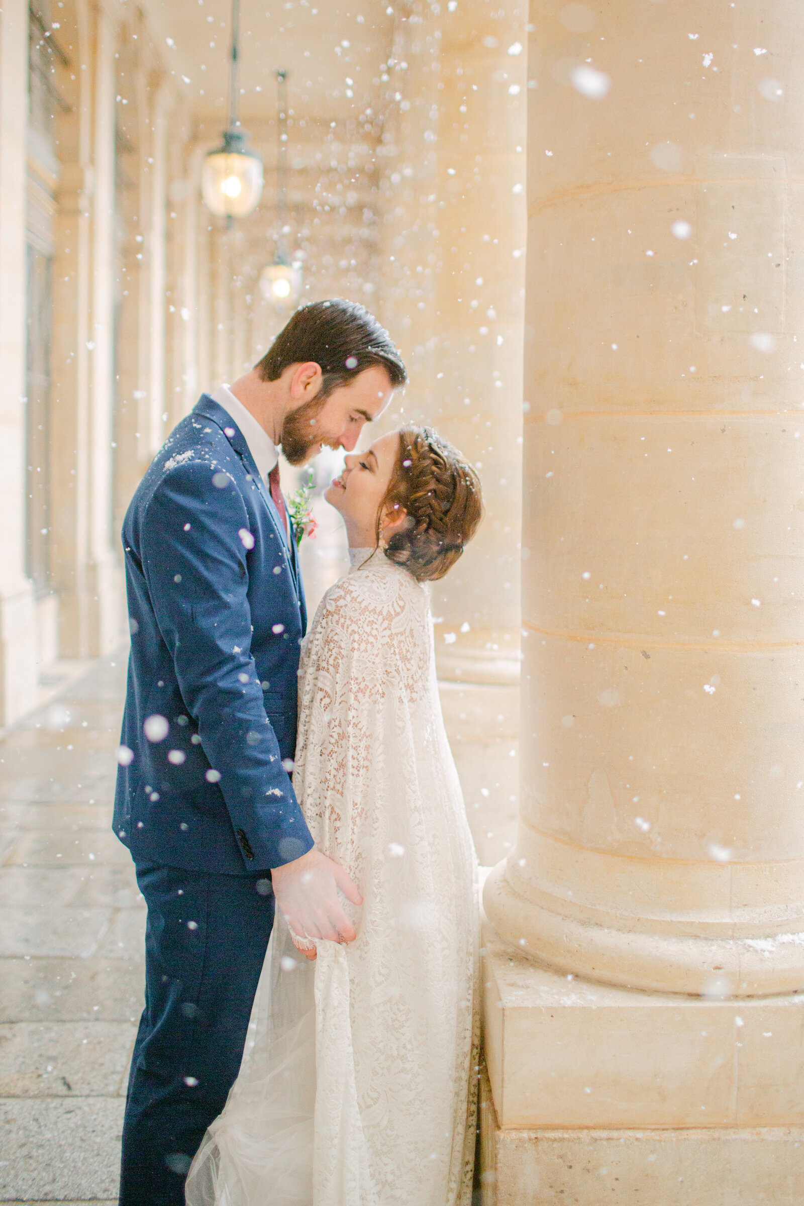 groom facing bride as snow falls around them