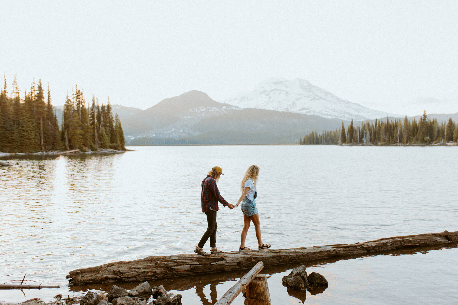 couple holding hands on a log