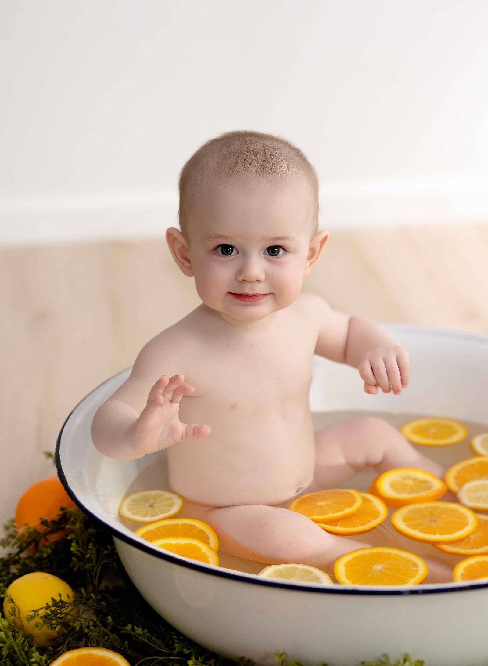 Baby sitting in basin tub smiling with oranges and lemon slices in water. Baby Photo taken by Jenni Nikki Photography at Atlanta Photo studio.