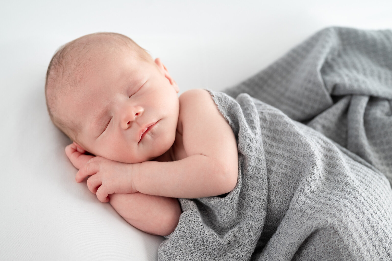 A baby sleeping  on his side during newborn photos at a studio in alabama