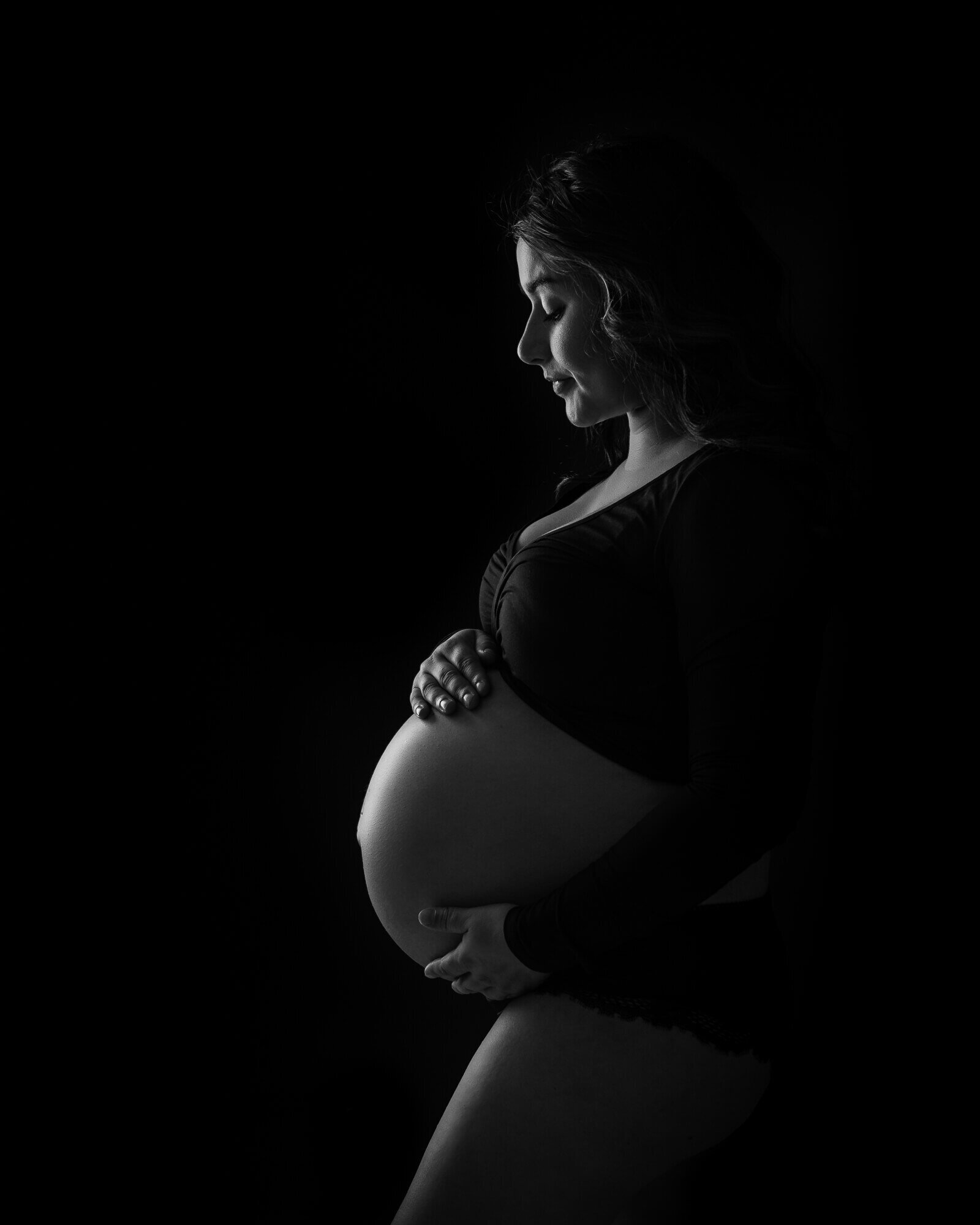 low-key rim lighting profile picture of pregnant woman