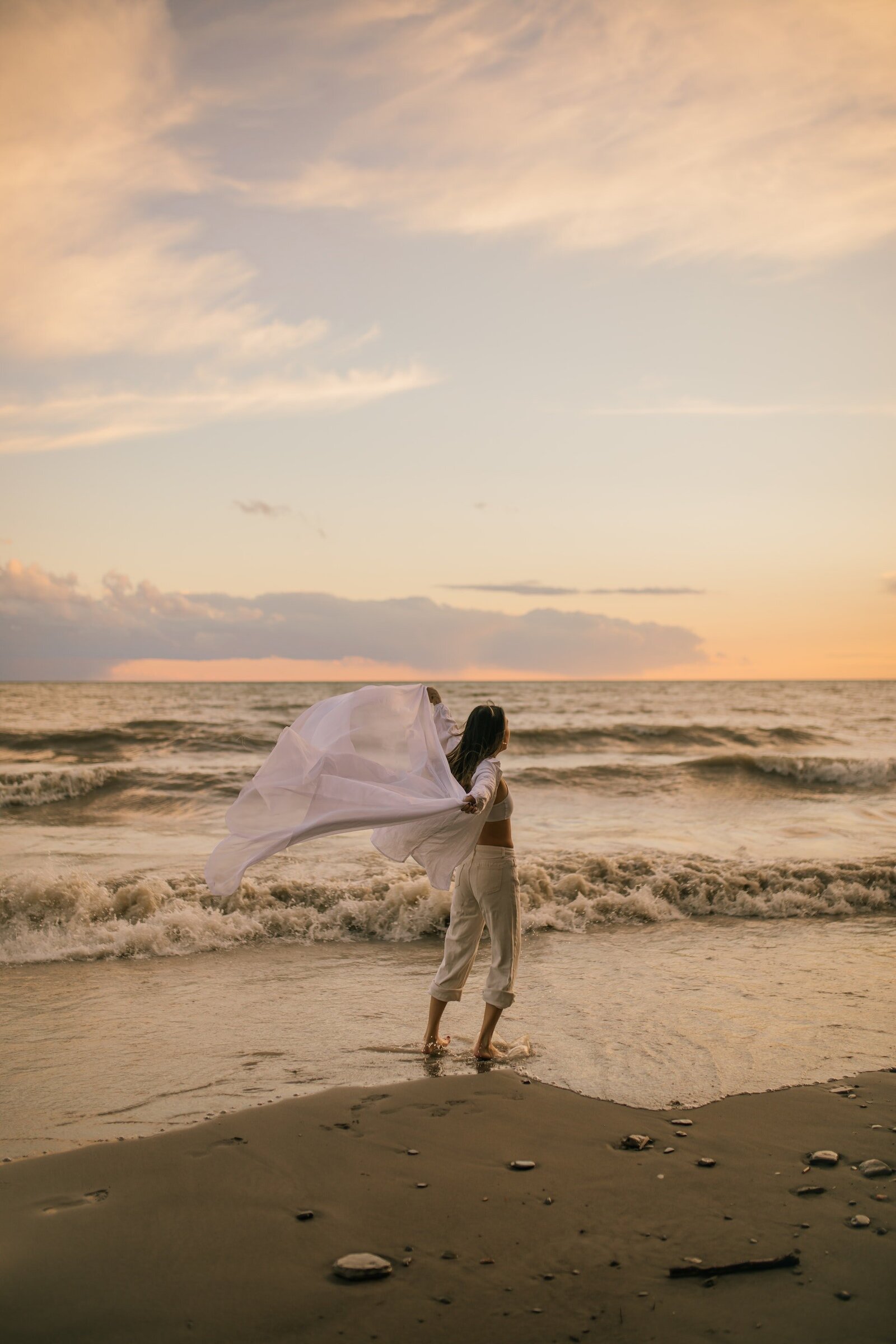 back-of-woman-walking-on-beach-at-sunset