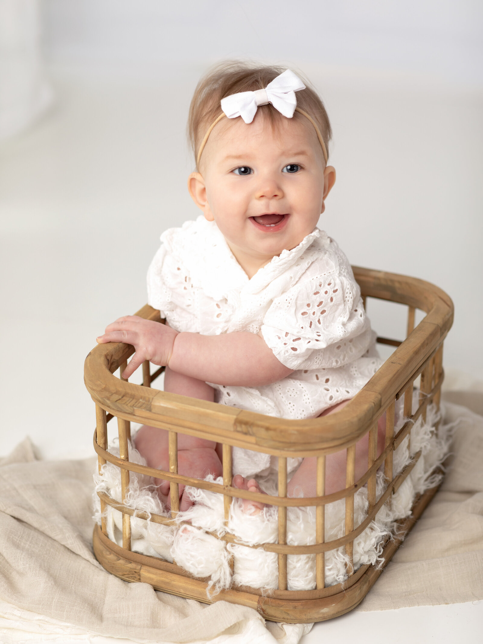 6 month old girl in white outfit sitting in basket for family photos cleveland family photography