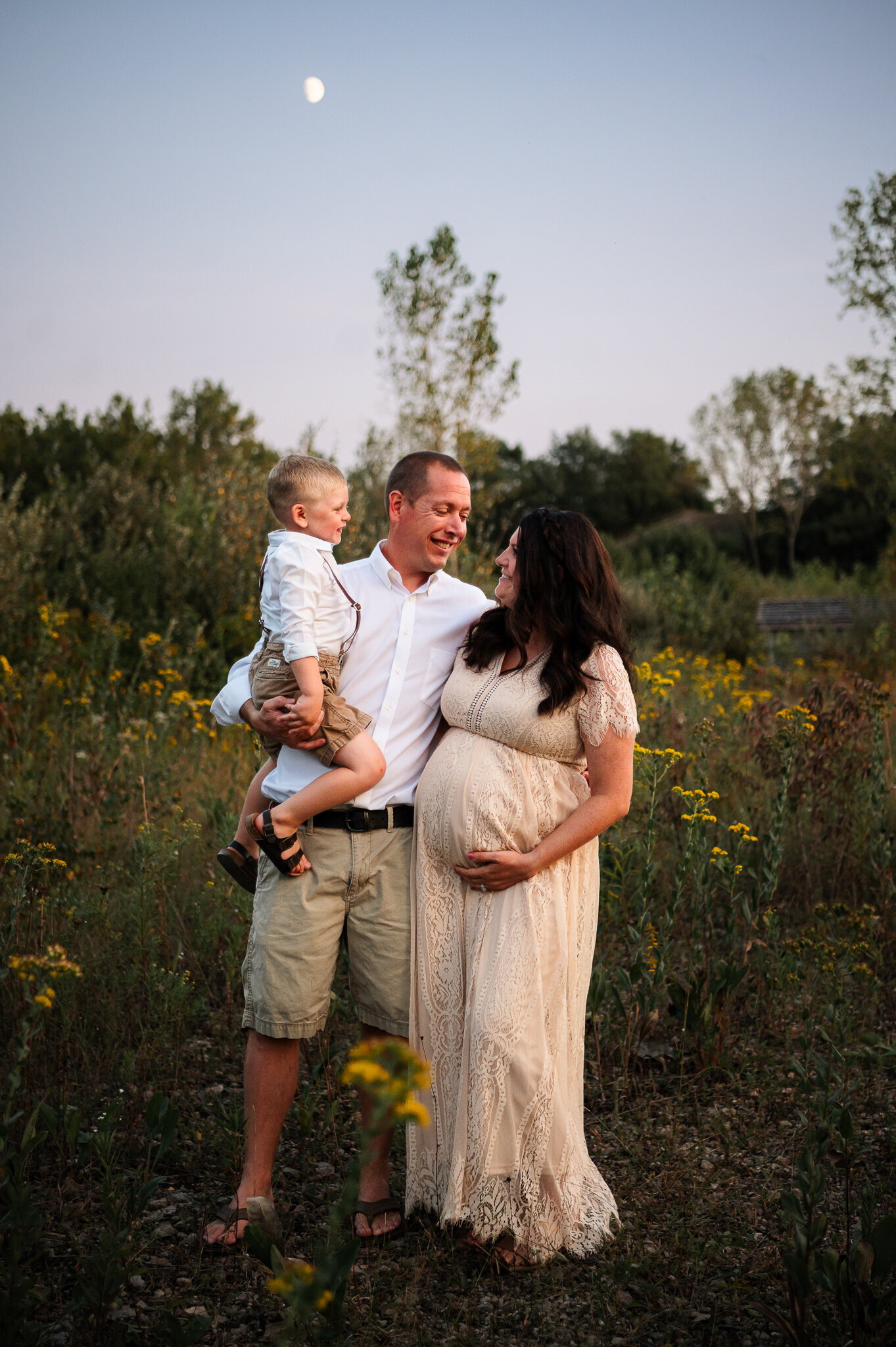 Family maternity session outdoor pregnant woman holding belly with family