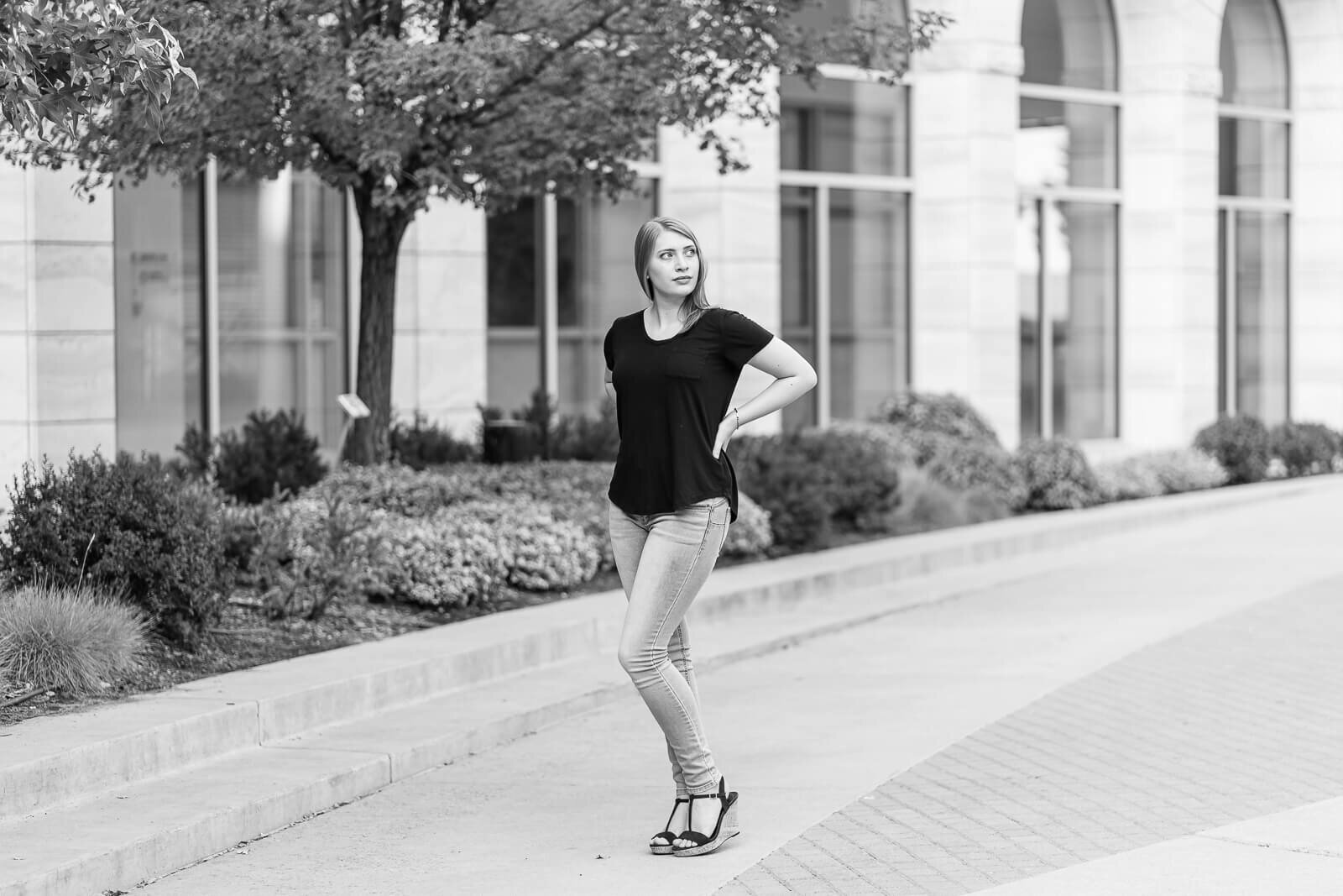 Black and white Salt Lake City senior photography of a high school senior girl standing with her hands on her hips on the grounds of BYU in Provo