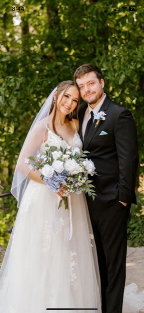 Groom in black tuxedo and bride in flowing wedding dress with bride holding a white and blue hydrangea bridal bouquet