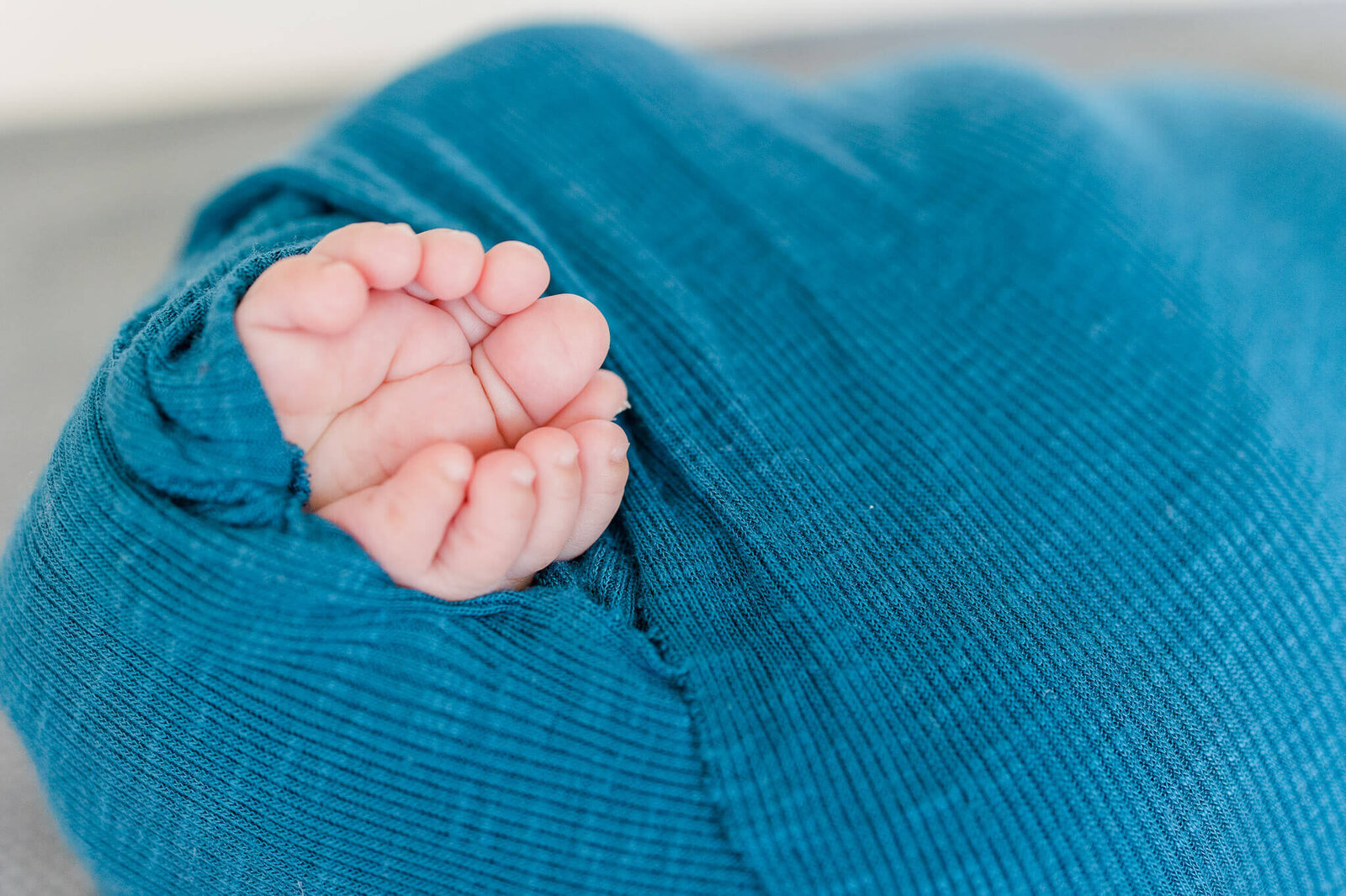 A close-up of a newborn boy's toes wrapped in teal.