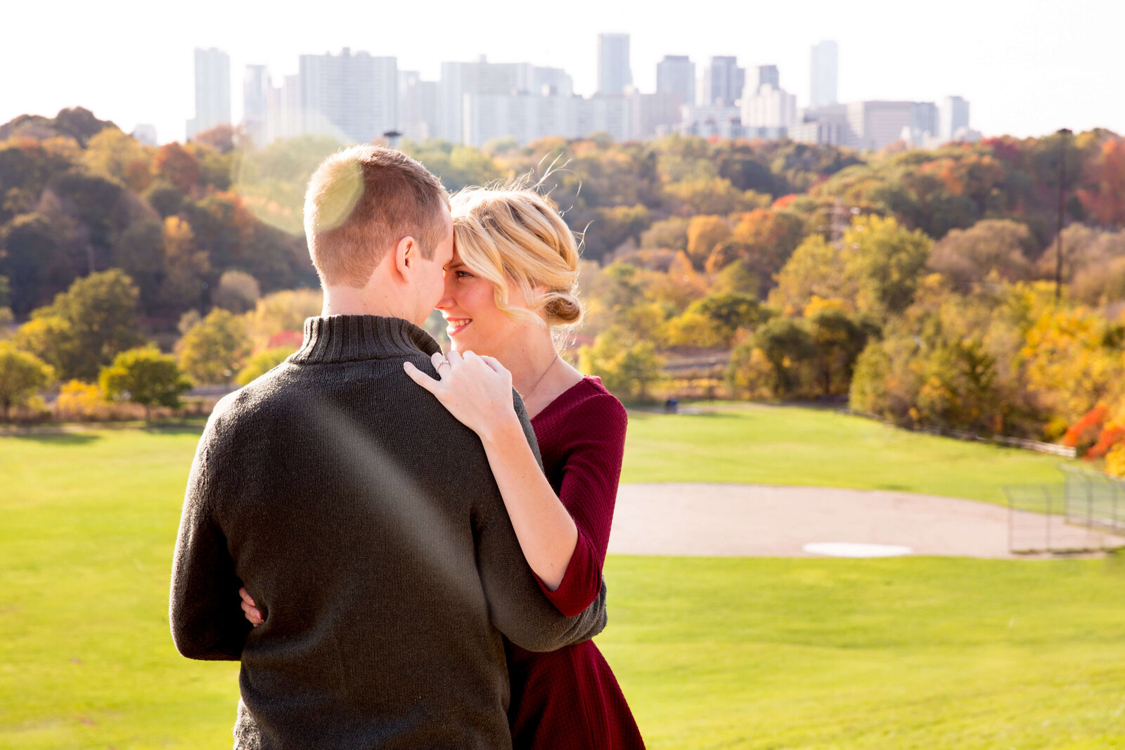 Couple embrace atop a hill overlooking fall colours in Toronto