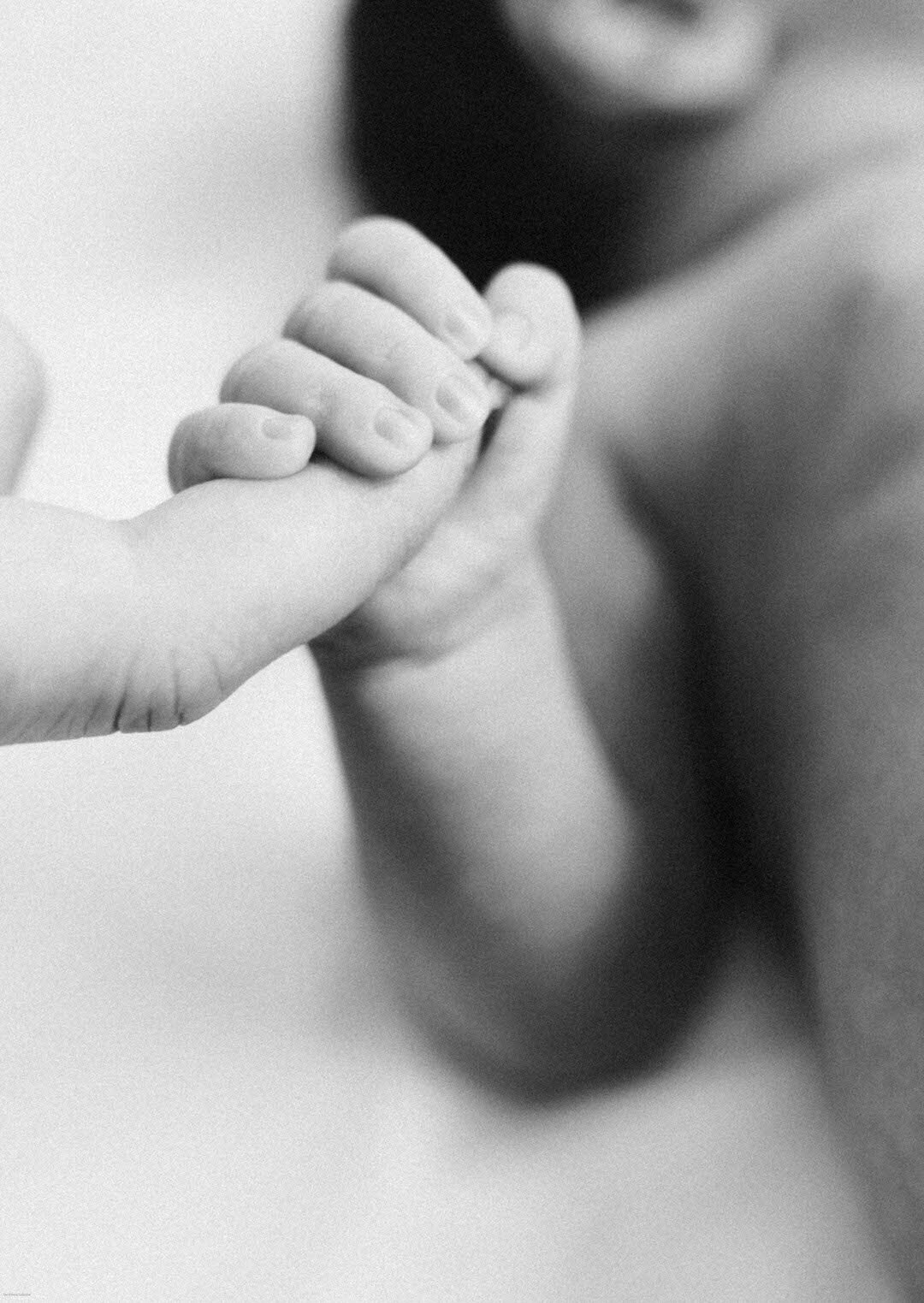 close up black and white photo of newborn baby holding moms finger