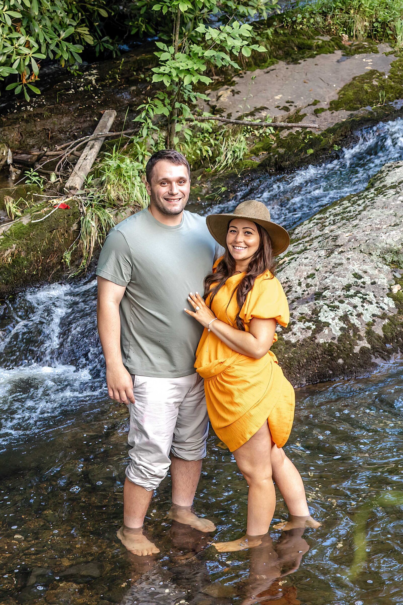 A couple standing in a serene waterfall setting at Chetola Resort in Blowing Rock, NC, with natural beauty surrounding them. This setting embodies the charm of artistic wedding photography, ideal for couples looking for unique and creative engagement photos in North Carolina.