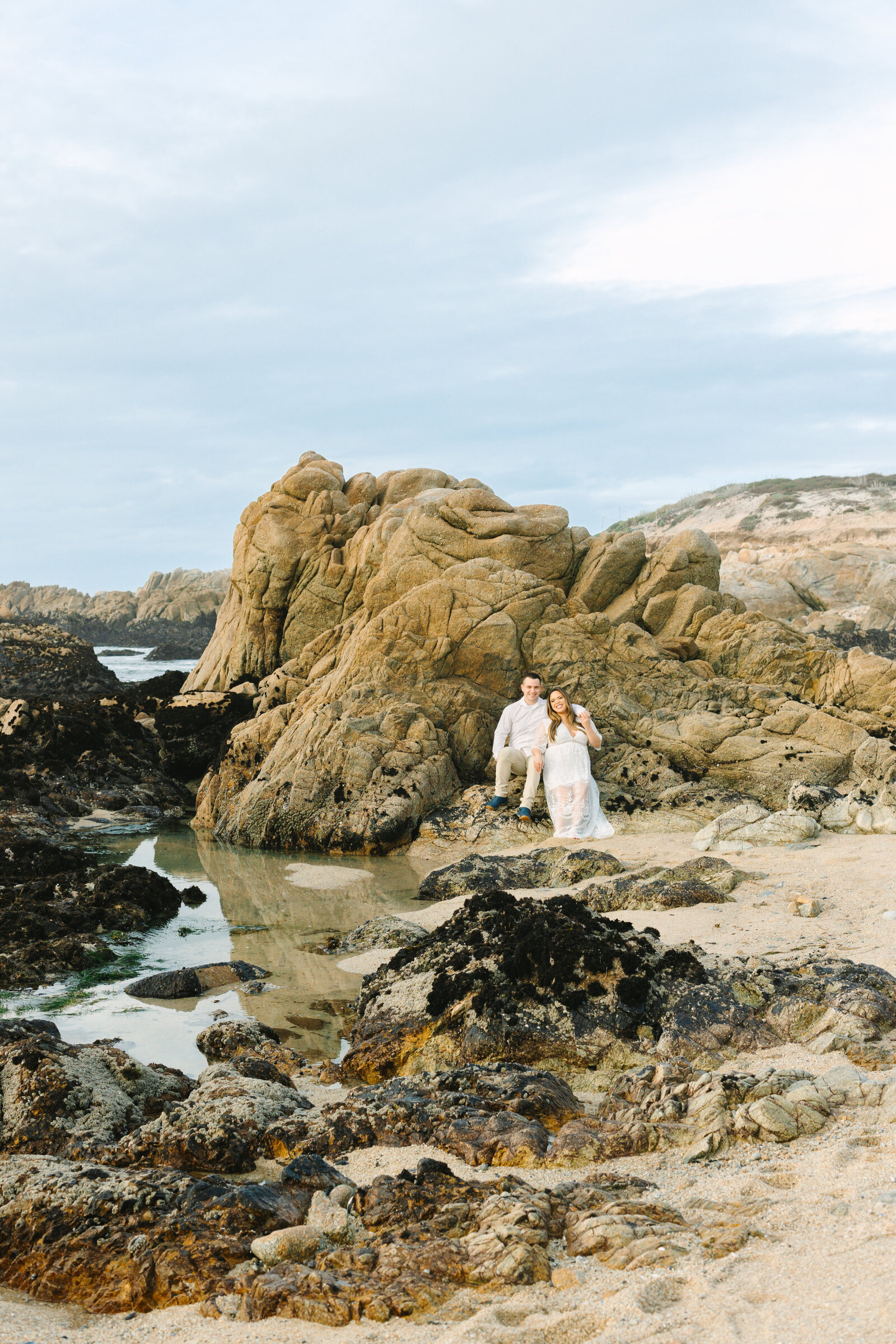An engaged man and woman take photos on the beach in Pacific Grove, Monterey, California near Big Sur.