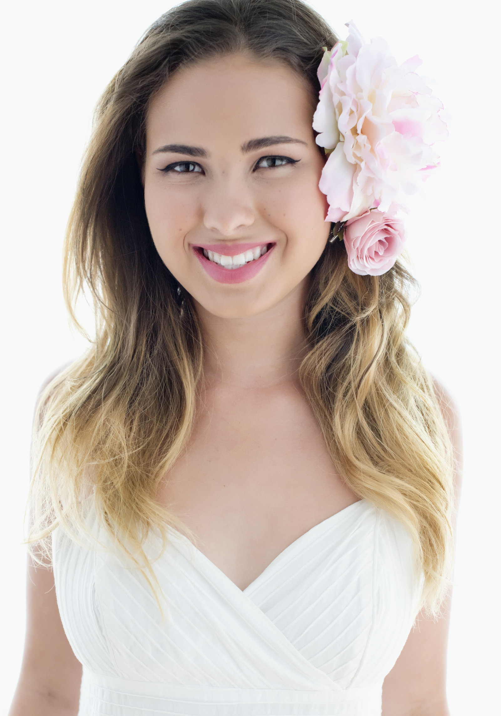 business headshot woman headshot Portrait  looking towards front  with   pink flower in the  hair . beautiful smile