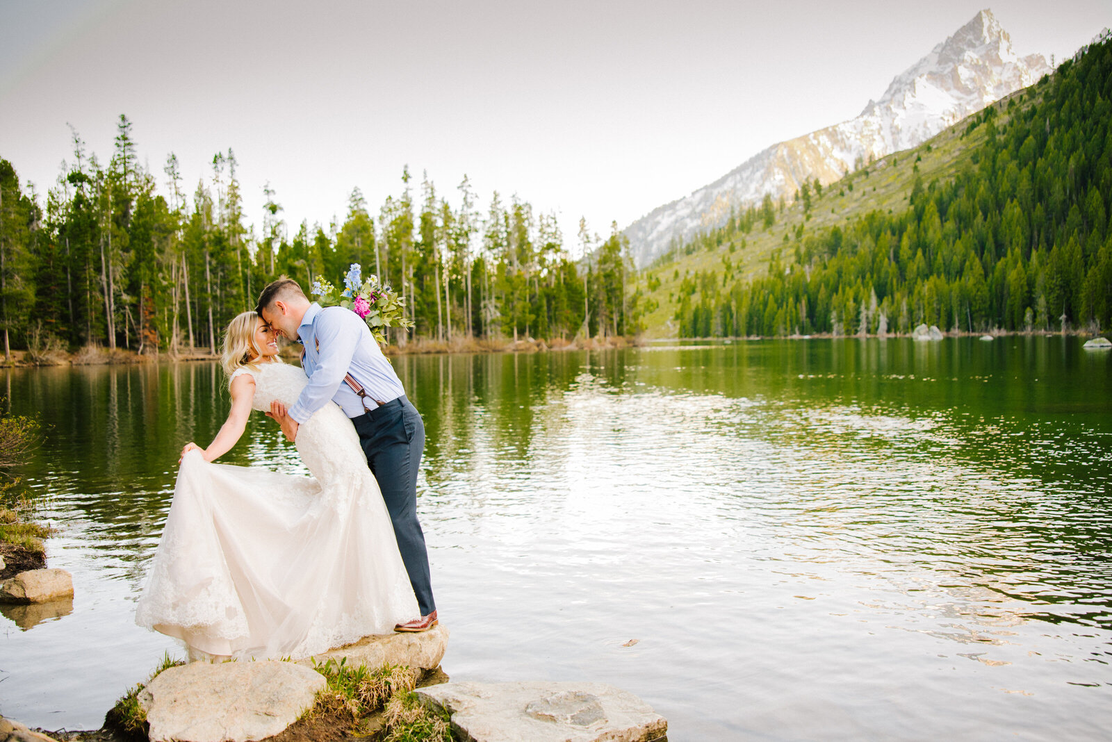 groom dips bride at lake in Jackson hole and Grand Teton National Park with Jackson hole wedding photographer