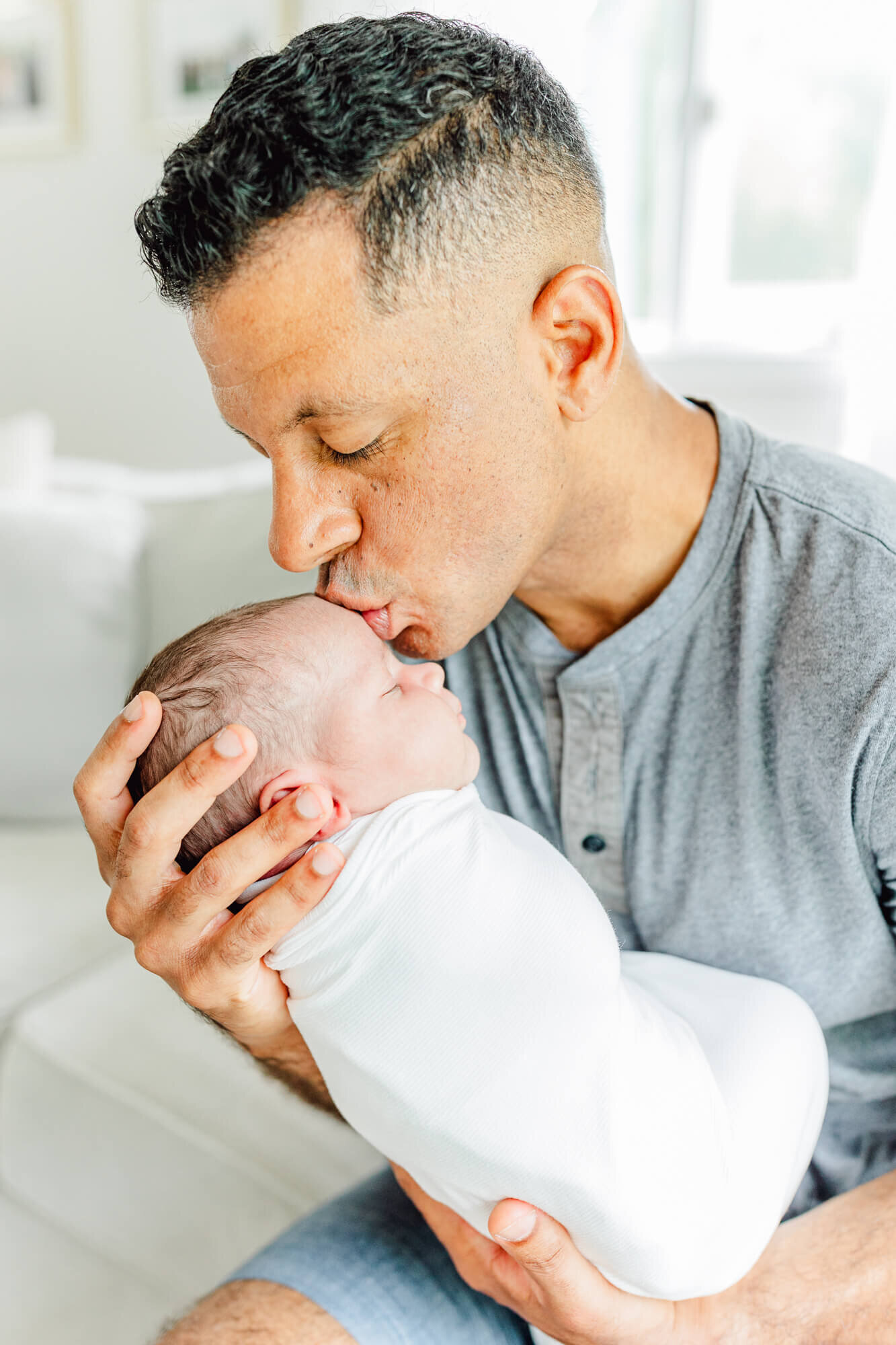 Dad bending down to kiss the newborn in his arms