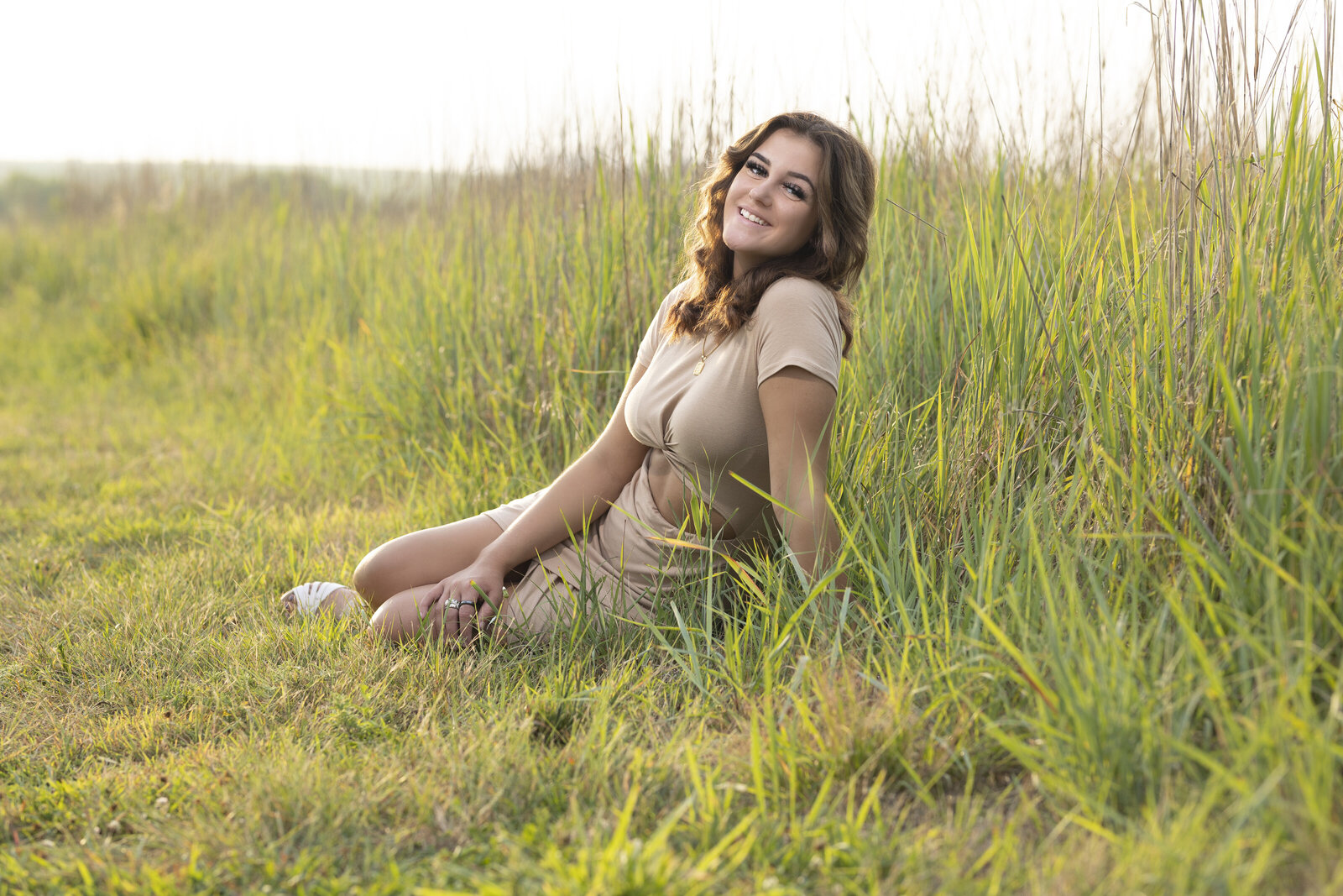 Senior Leah lounges in a field at Pioneers Park during a senior photo session
