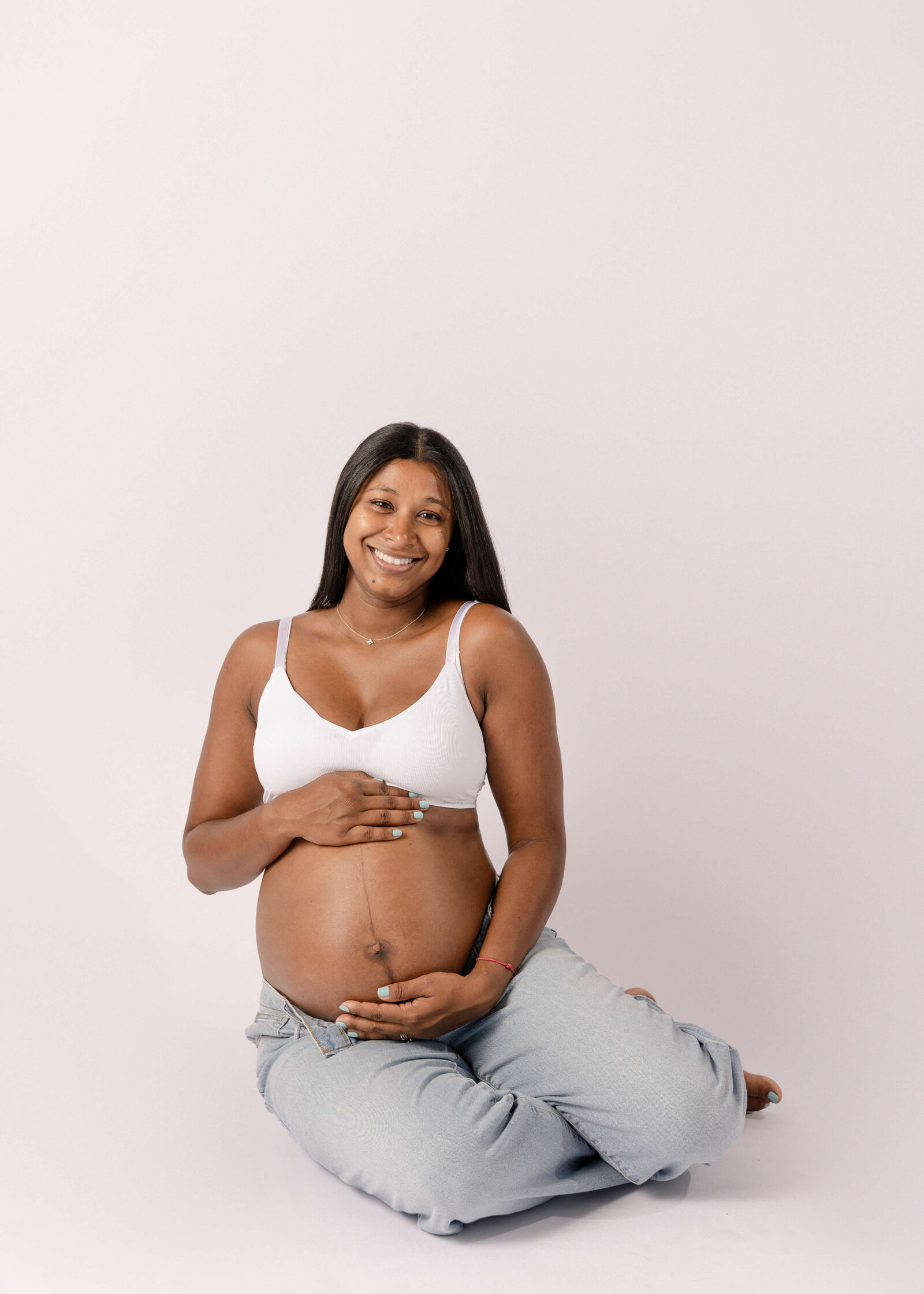 Maternity session in studio by Ashley Nicole Photography momma sitting on floor holding belly.