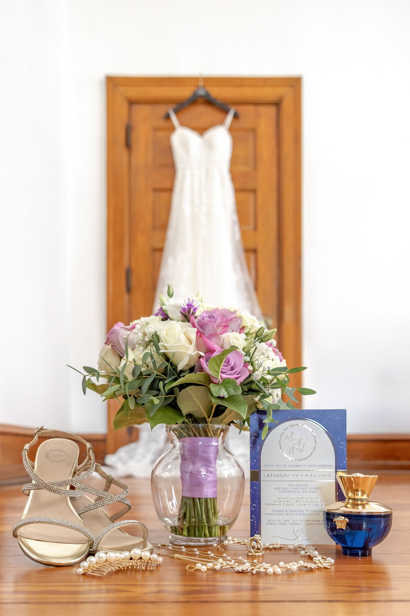 Bridal dress hanging elegantly in a well-lit room, accompanied by a bouquet and wedding stationery, captured in Coatesville, PA.