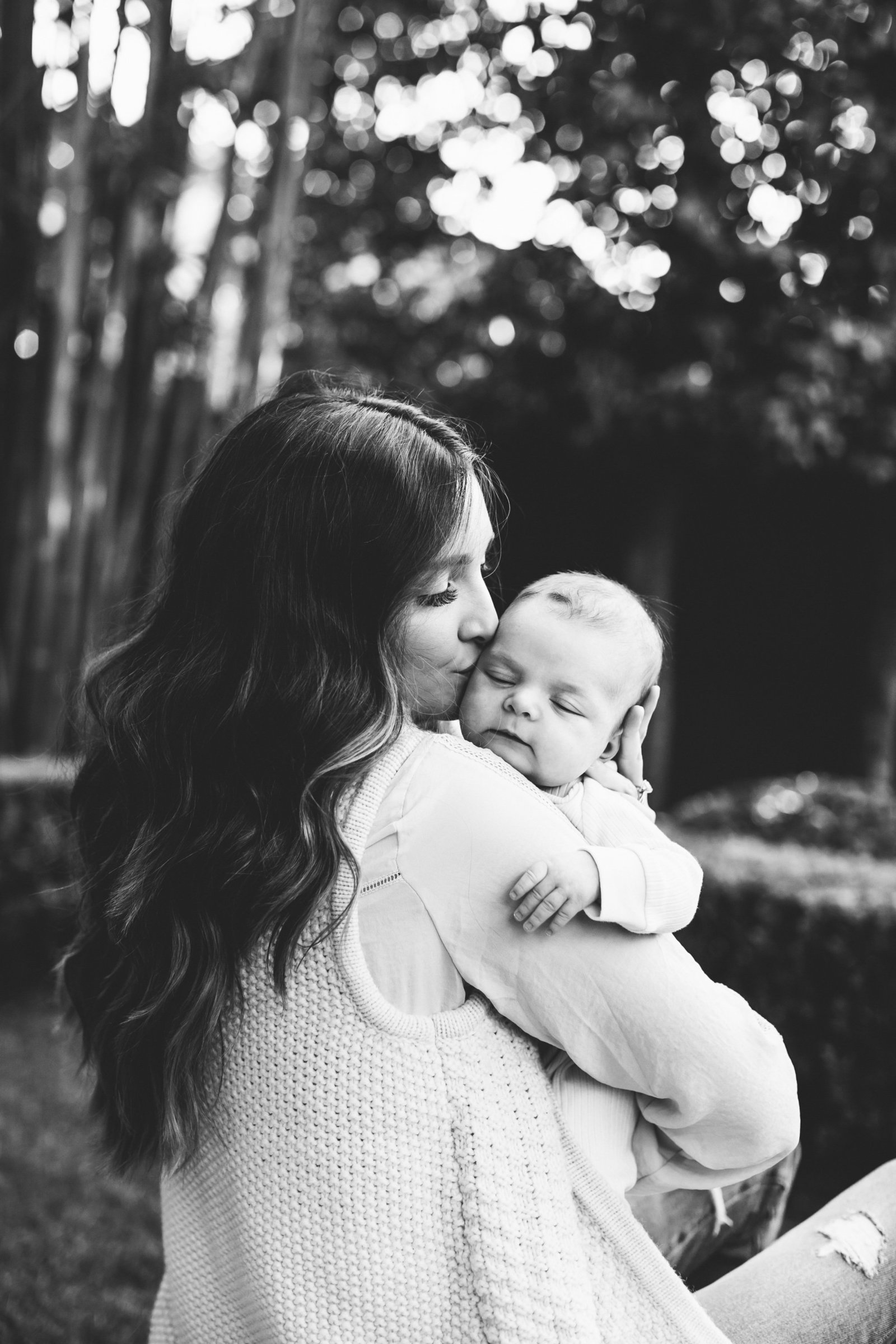 Classic black and white photo of mom kissing newborn