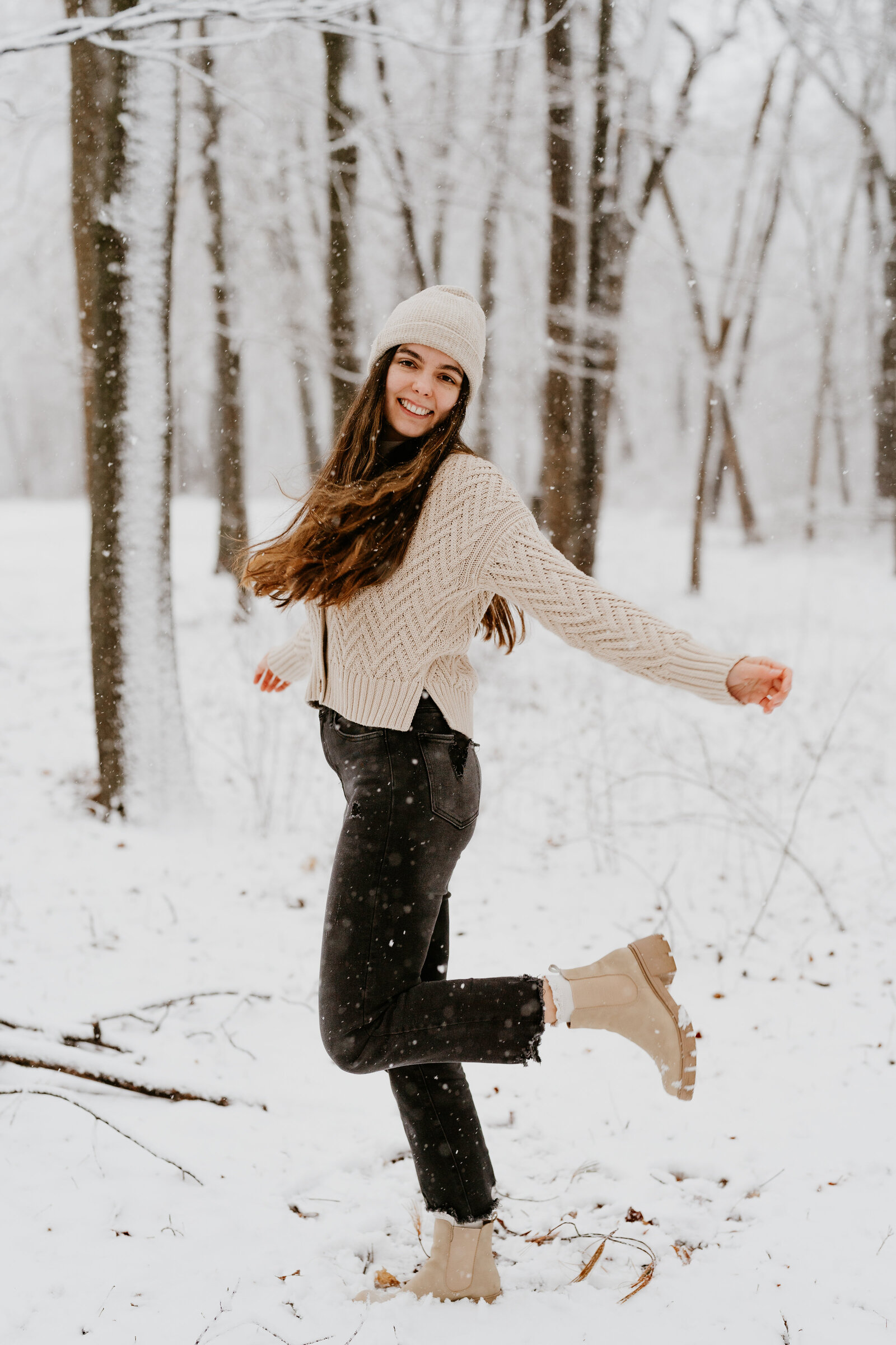 woman smiling while standing outside under the trees in the snow