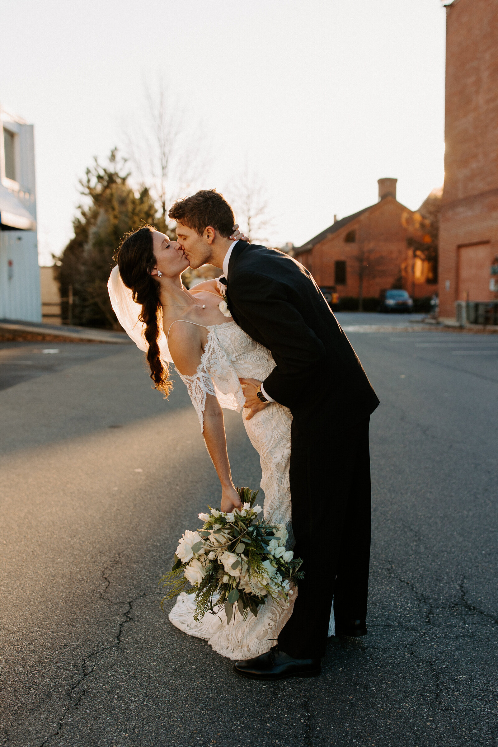 bride and groom kissing while they lean back slightly