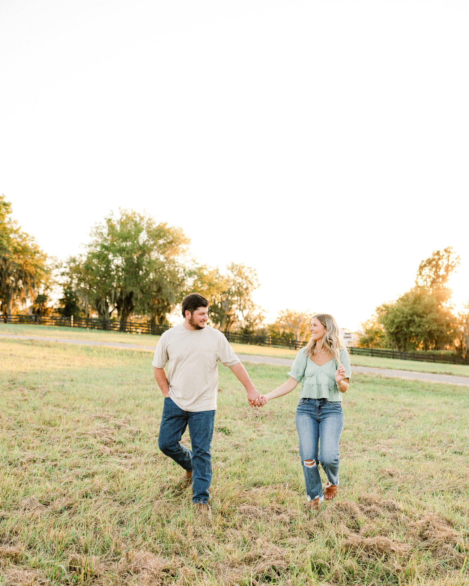 Kelby and Mason holding hands by a peaceful Alabama river, captured by Abby Bell Photography. Romantic fine art photography.