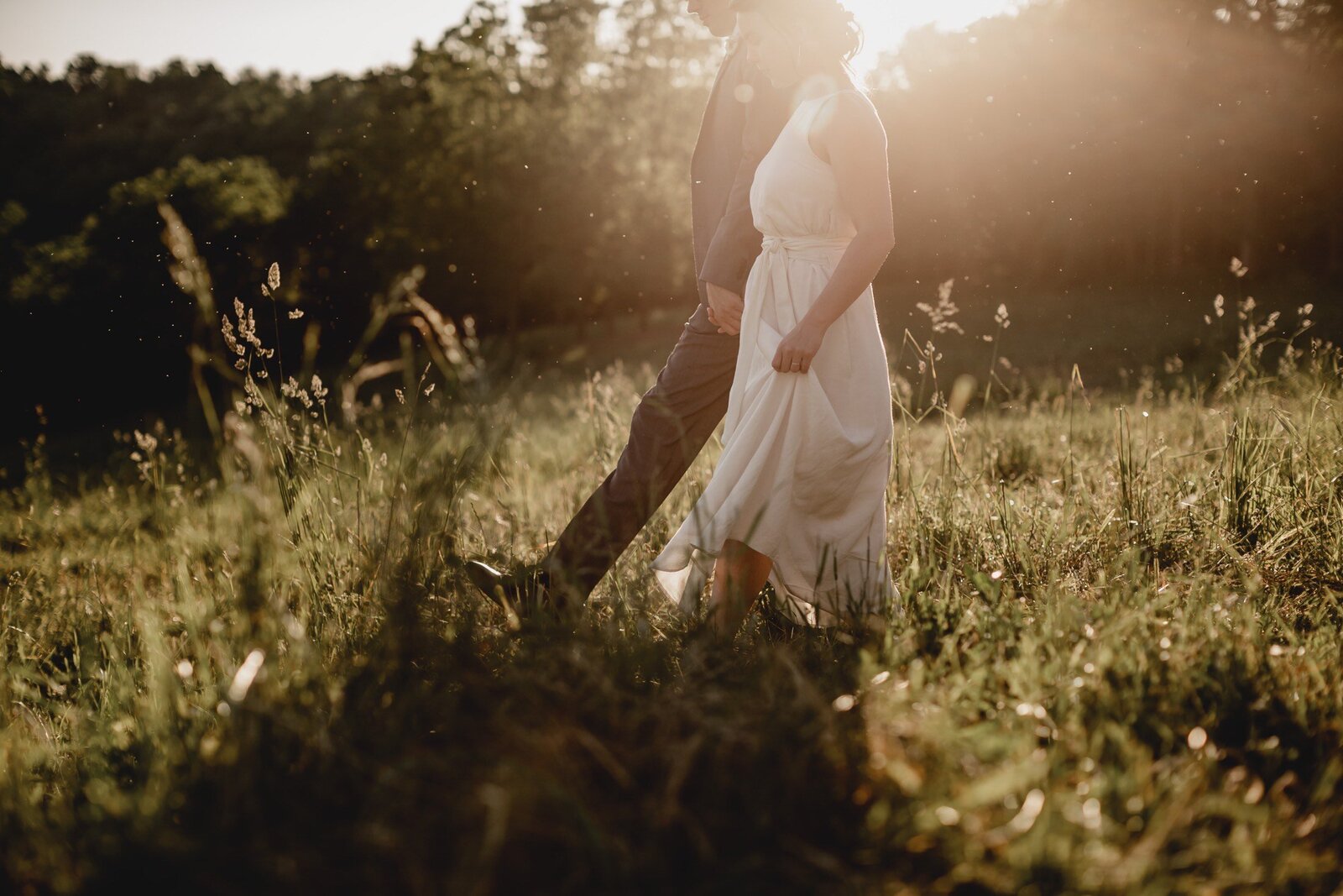 bride-groom-walking-through-sunlit-field
