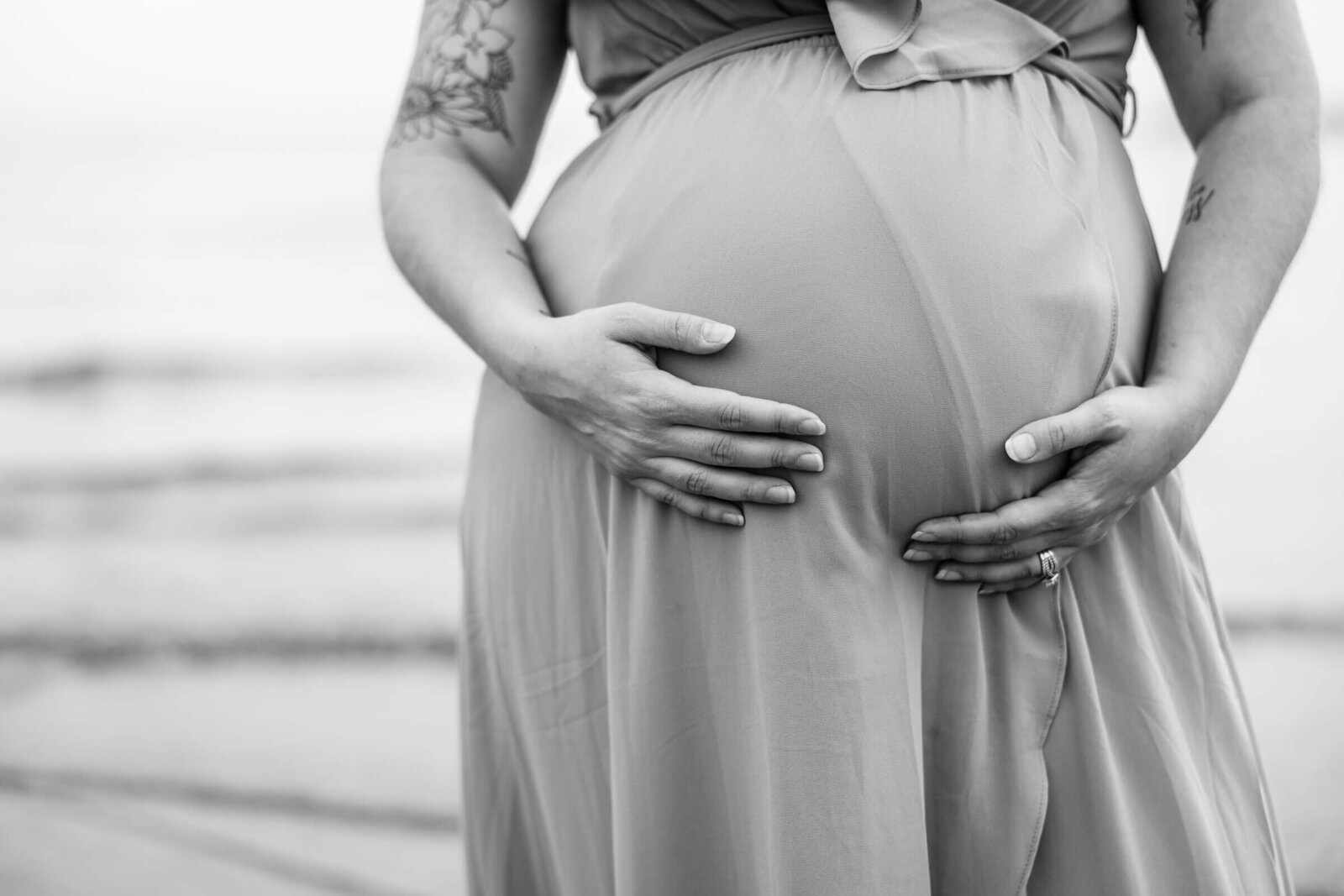 Dramatic black and white photo of a pregnant woman holding her belly.