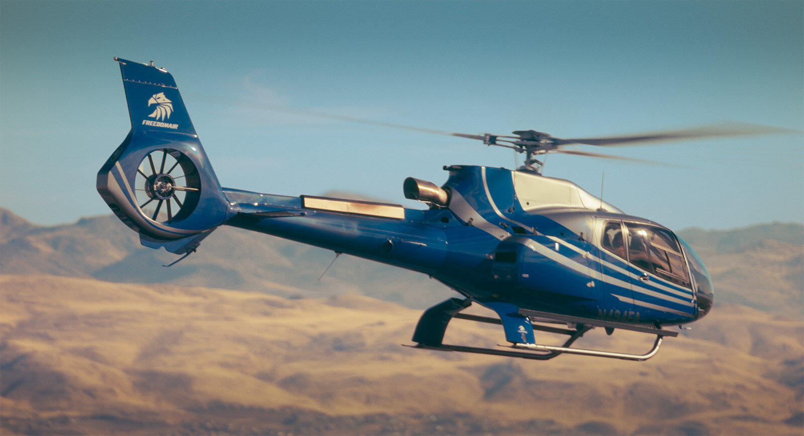 Blue helicopter flying over nevada mountain ranges