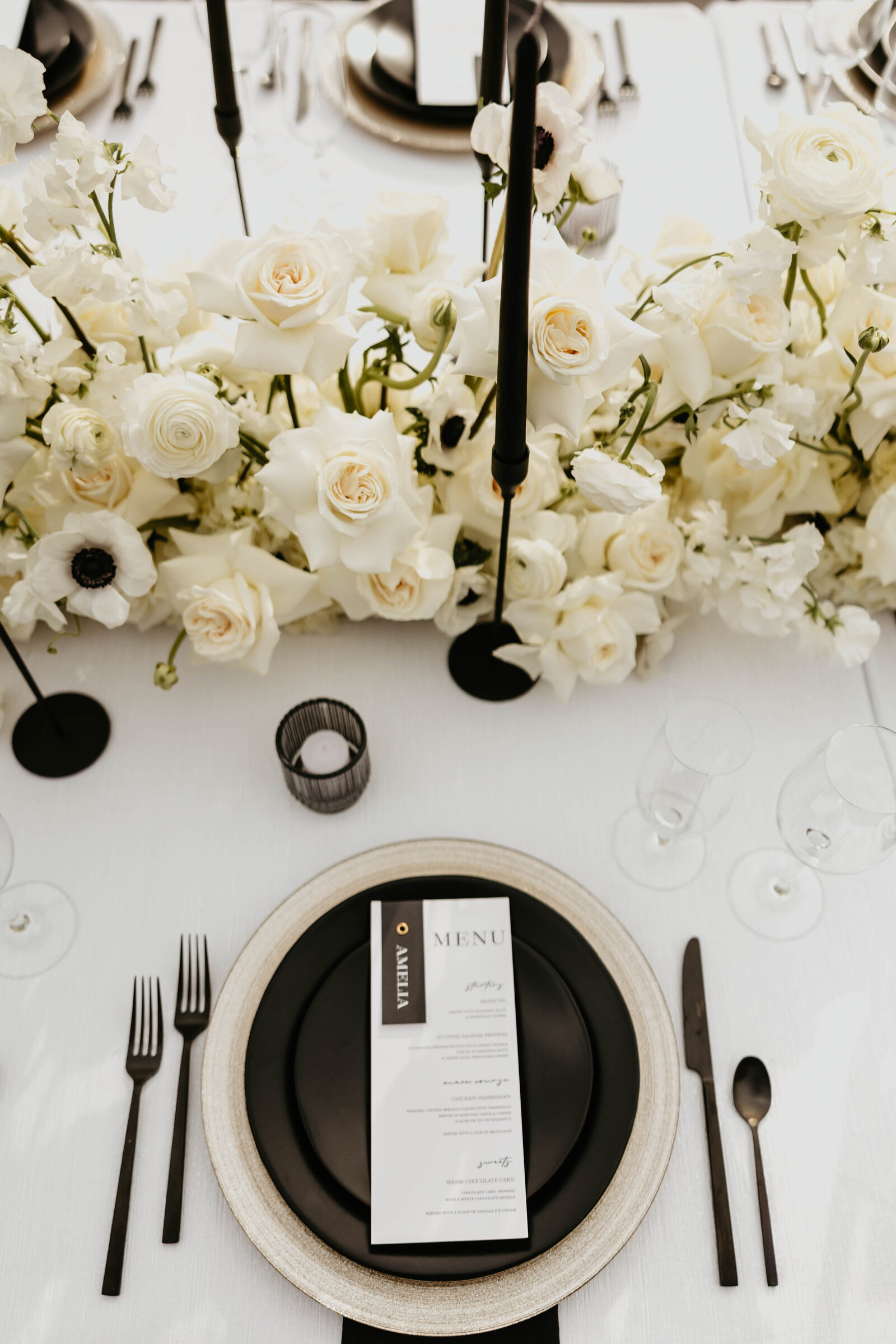Black and white wedding table scape with modern menu cards and white floral arrangement - Simply Bold Events, luxury wedding planner