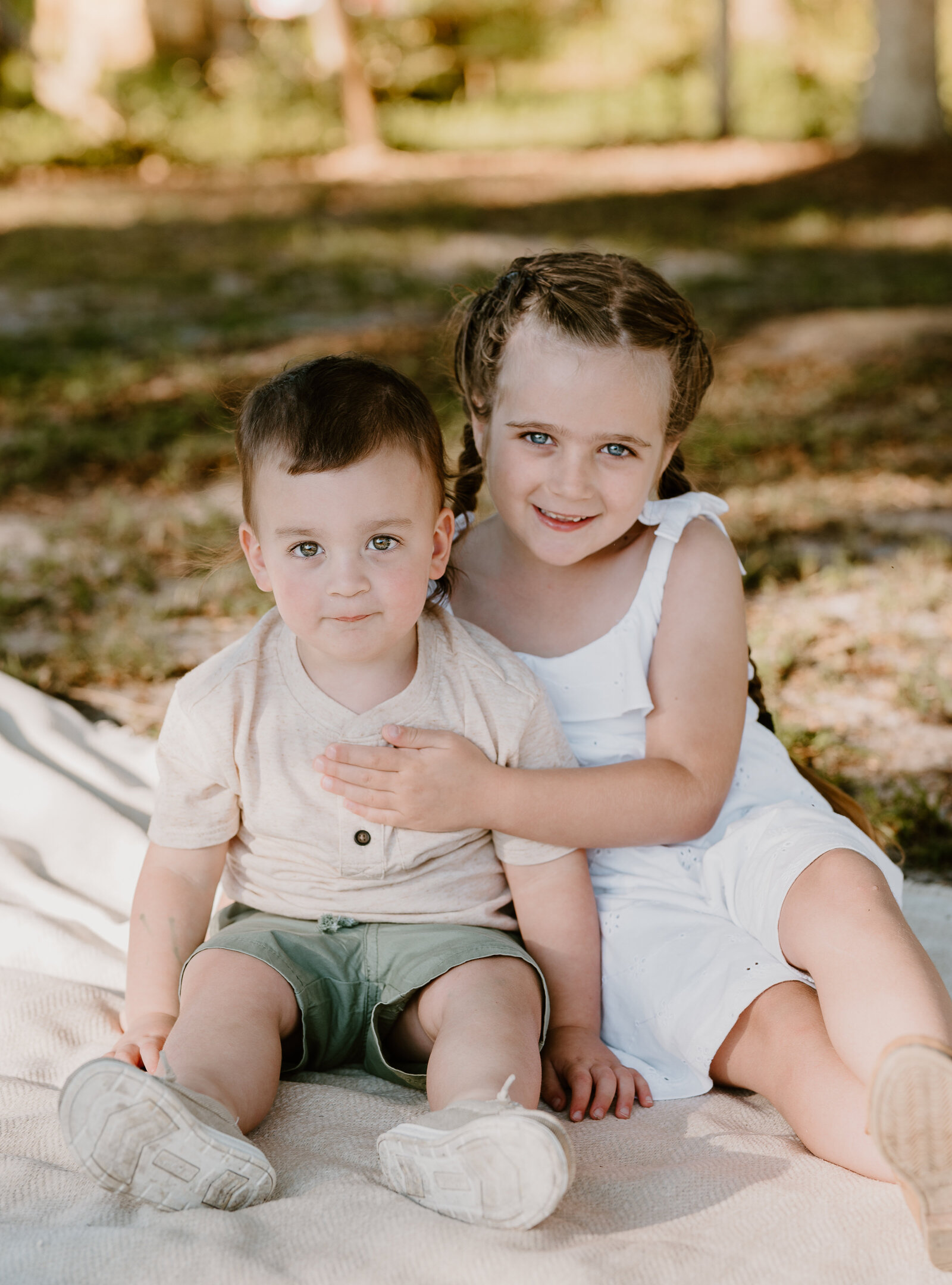 Two young children smiling outdoors during a natural lifestyle photo session in South Florida