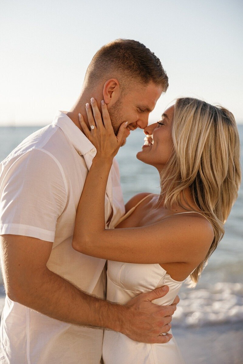couple smiling at each other and kissing by engagement photographer naples fl
