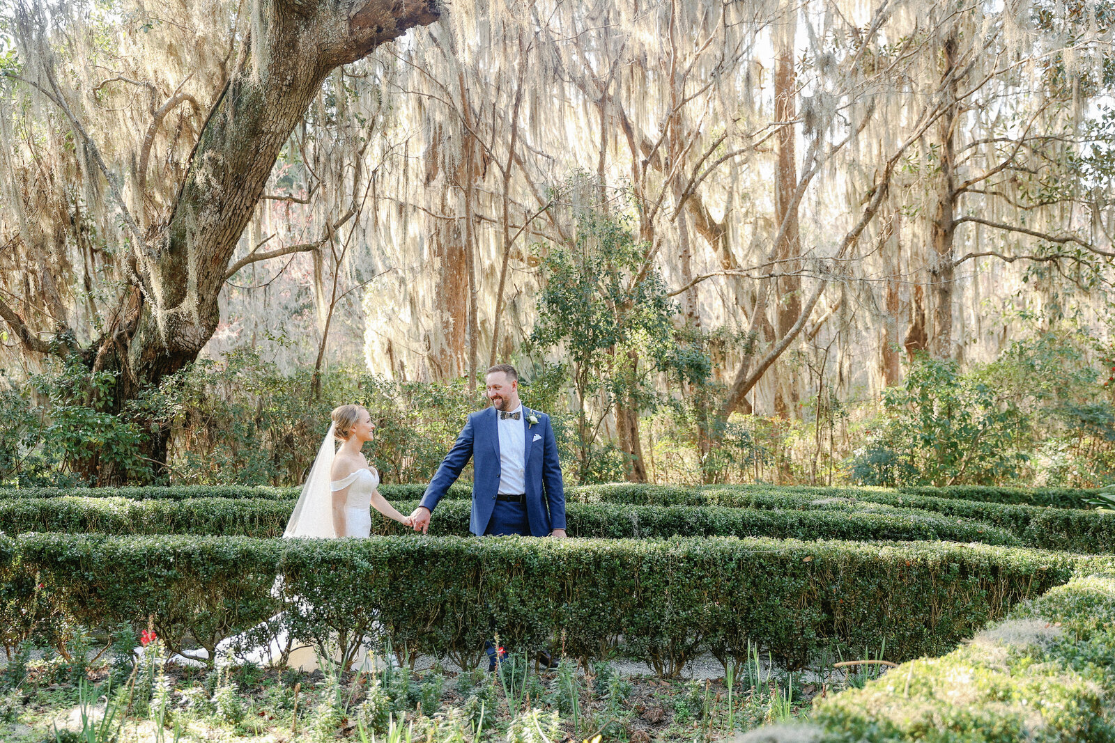 bride and groom walking amongst Spanish Moss oak trees