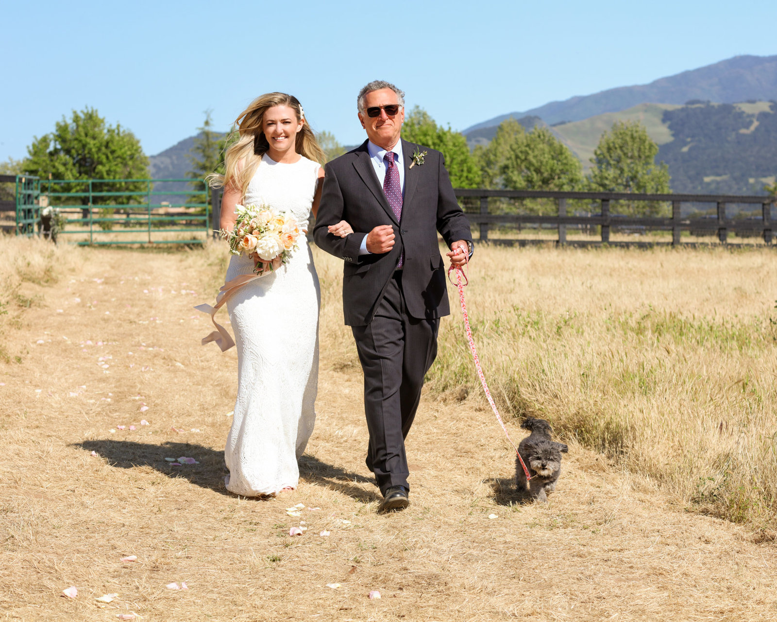 Couple in rustic wedding walk down the aisle, led by their adorable dog