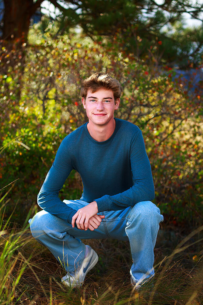 senior-high-school-senior-crouching-jeans-slate-blue-shirt-pine-trees-nature-erie-high-school