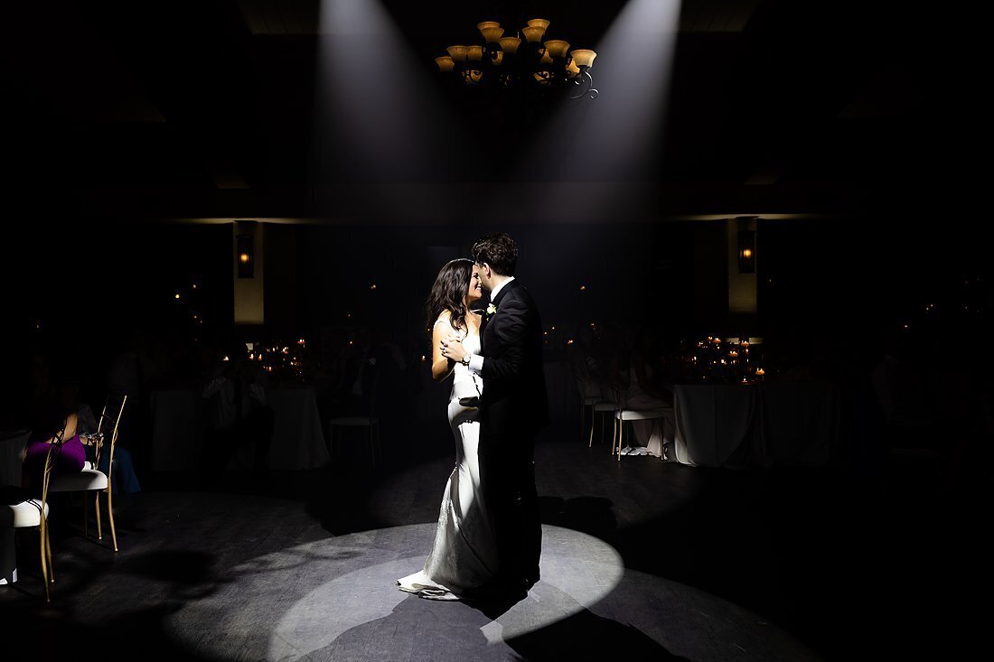 Newlywed-bride-and-groom-sharing-their-first-dance-together-at-their-reception-under-spotlights