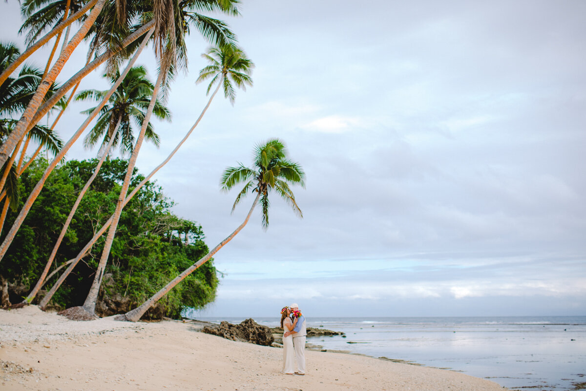 bride and groom on beautiful beach under a palm tree