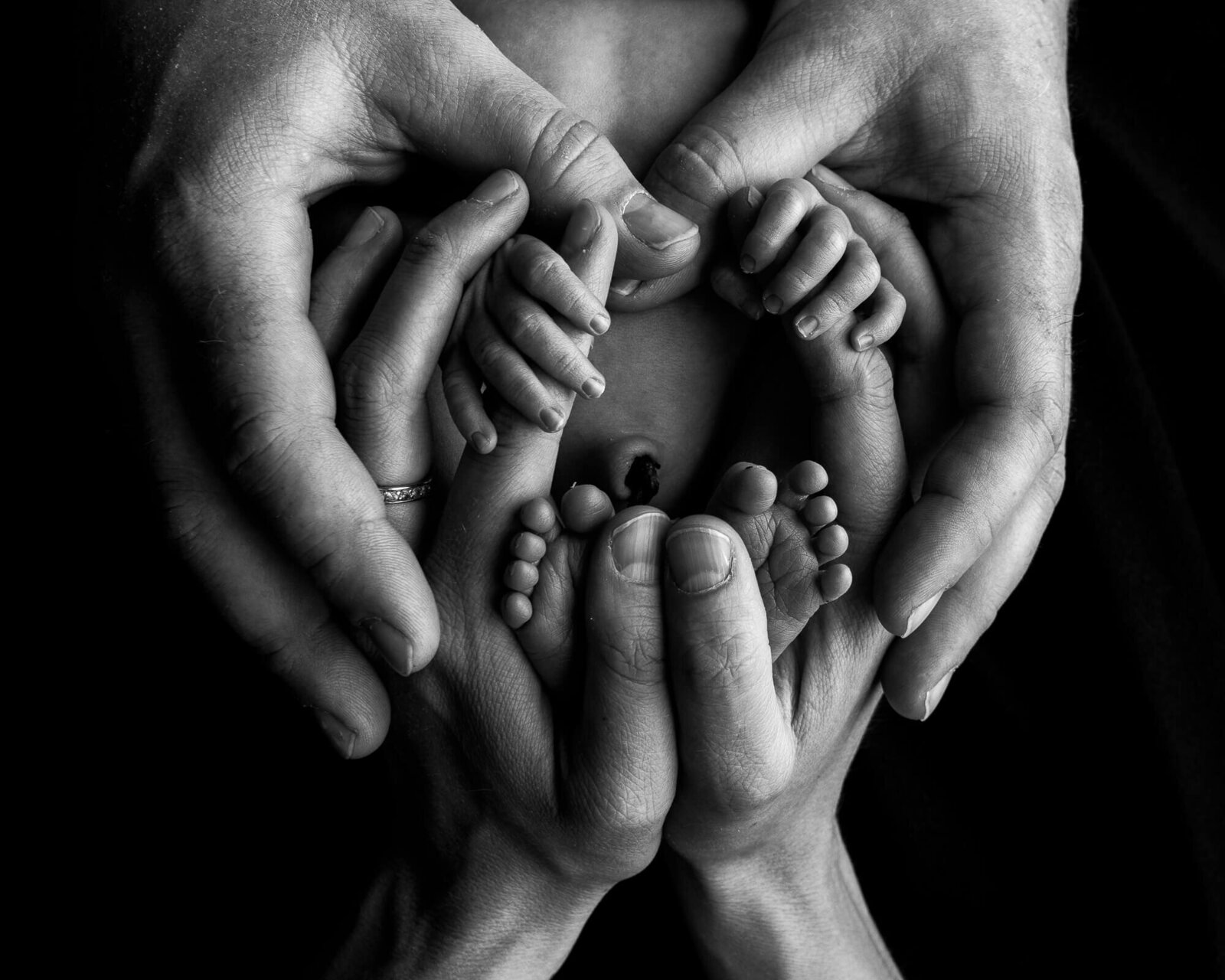 black and white image of baby and parents hands