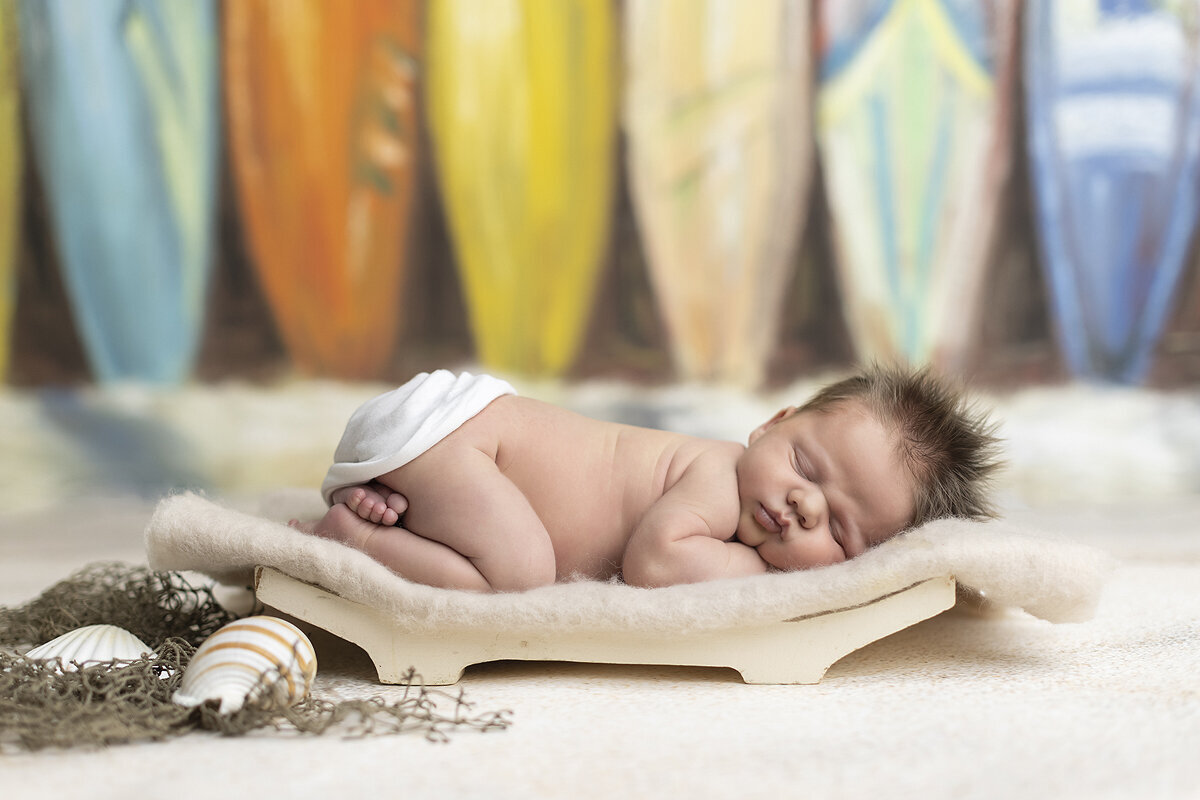 Newborn boy posed with surf boards, a Dallas newborn photographer.