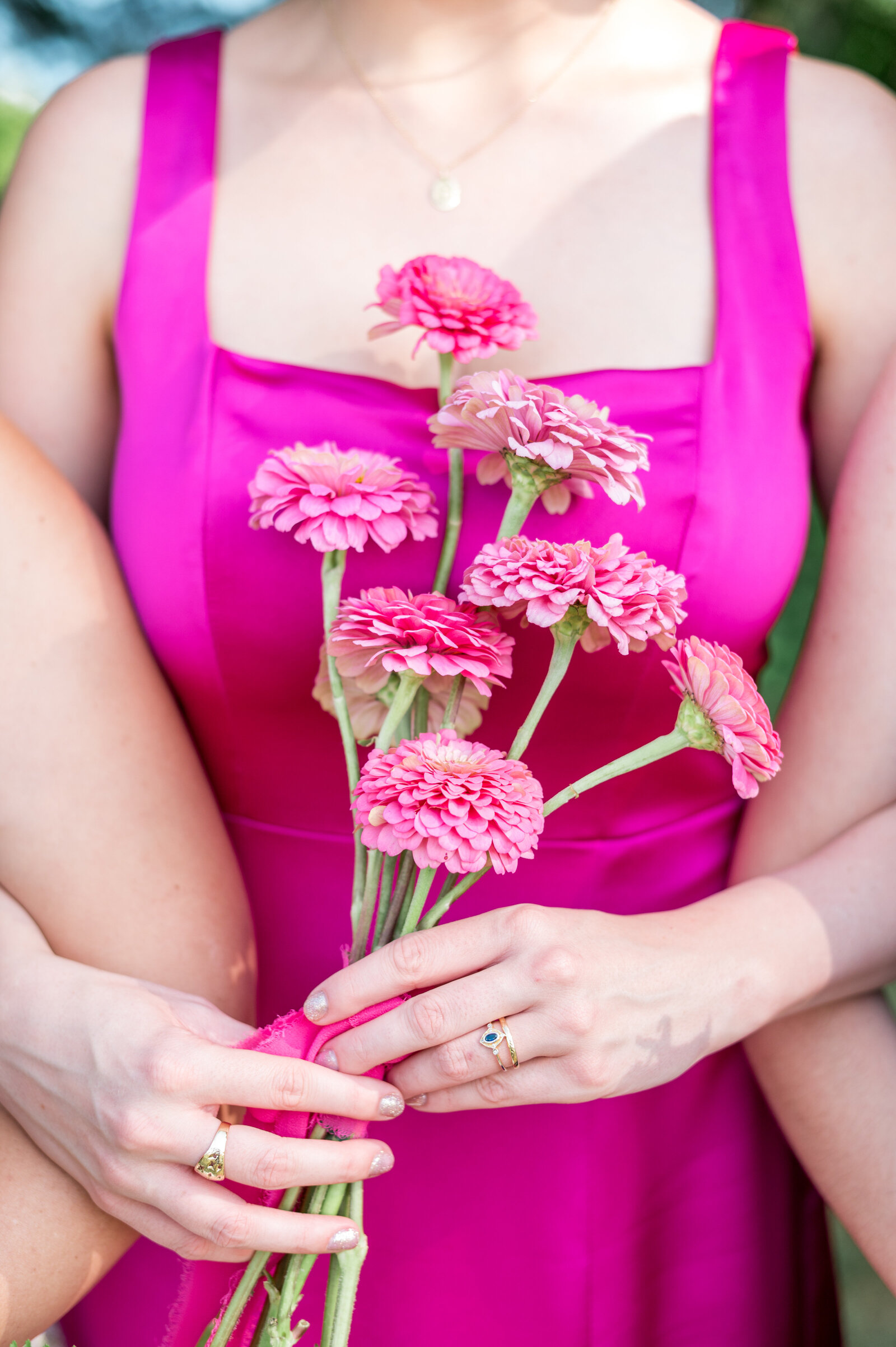 Bridesmaid in vibrant pink dress holding bright florals at Fruitlands Museum wedding — bright and airy detail photo by Sarah Surette Photography