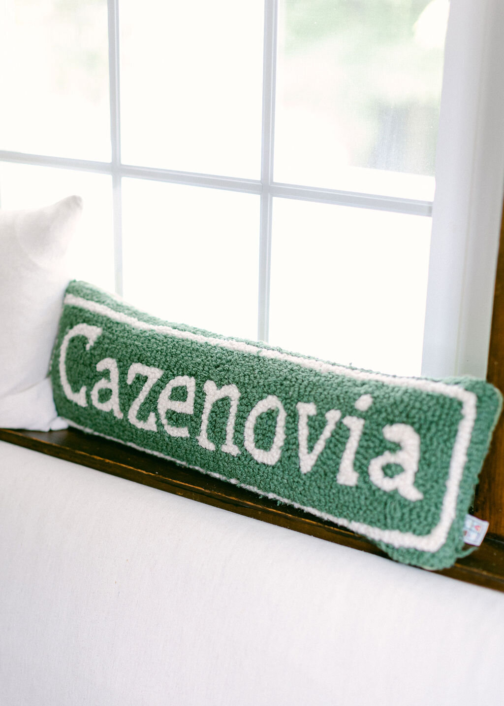 hunter green hand punched pillow with white letters spelling "Cazenovia"