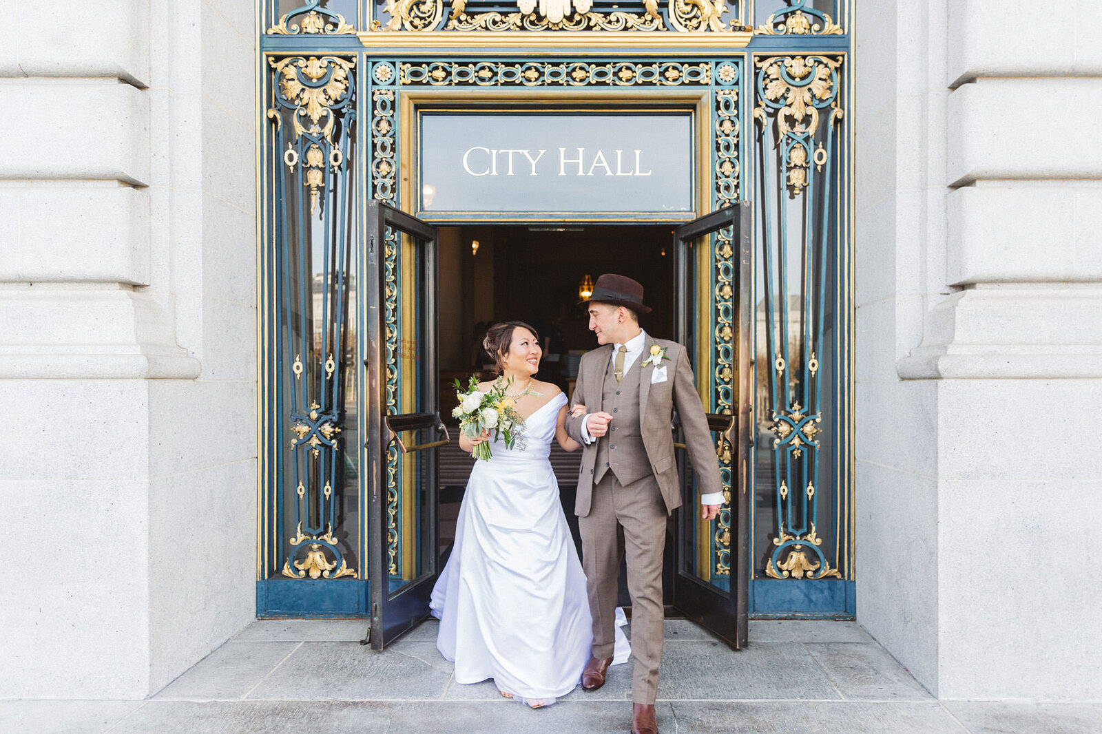 asian american couple exiting san francisco city hall after wedding