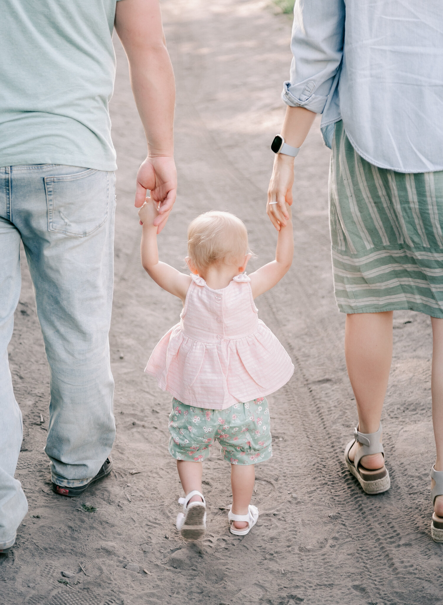 A small child holds her parents hands during a family session. Photo by Diane Owen.