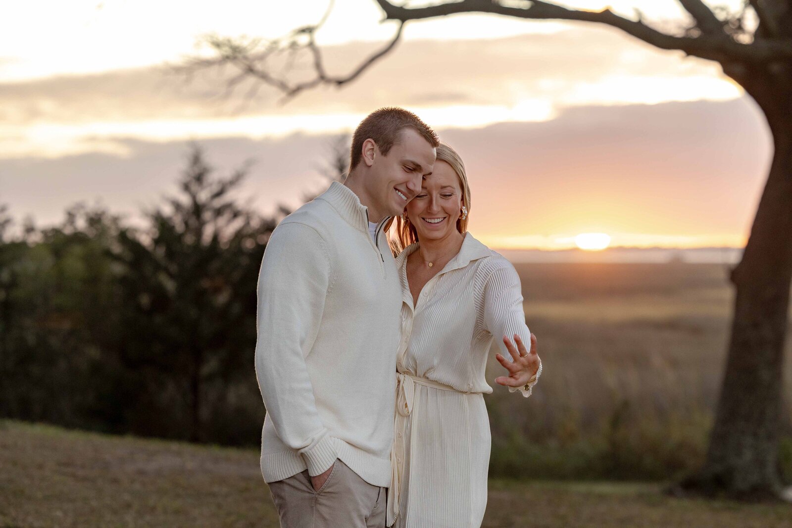 A couple joyfully admiring an engagement ring at sunset in Wilmington, NC. This intimate moment captures the essence of elegant wedding photography, appealing to couples interested in capturing genuine moments in their engagement photos.