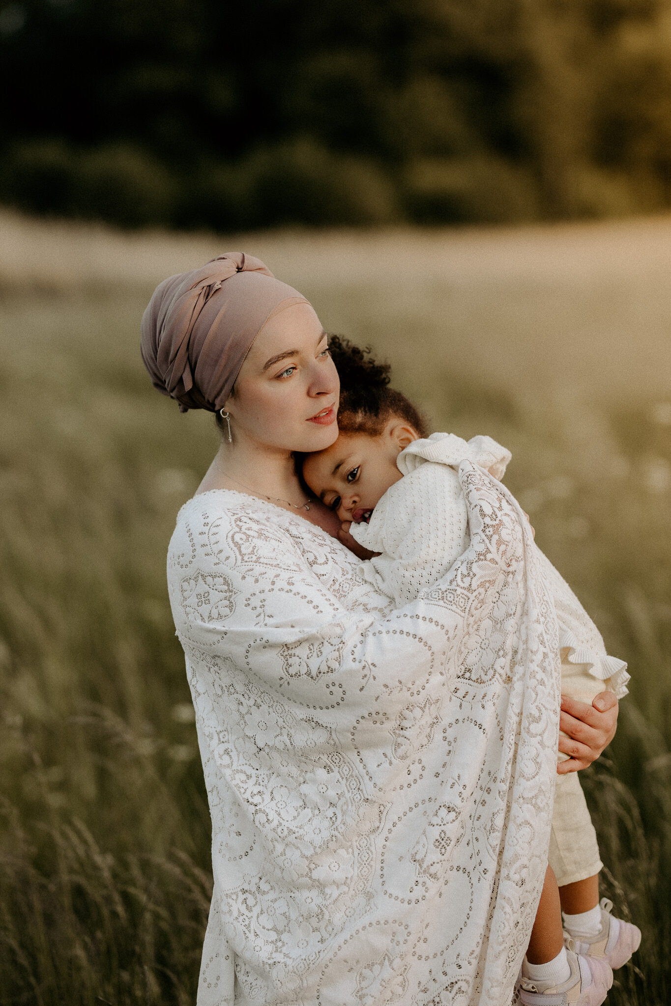 en mamma med hijab håller om sin dotter på ett fält