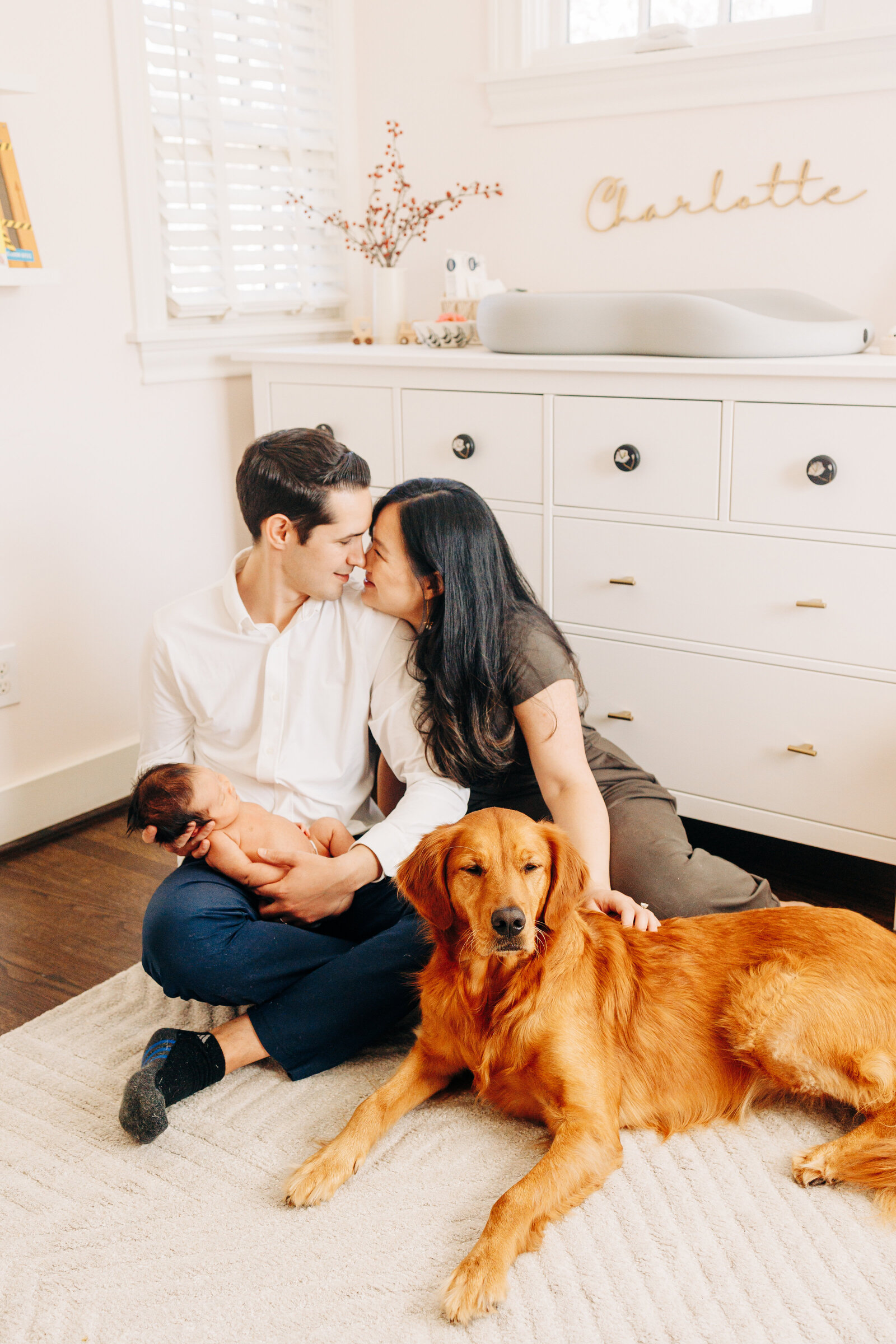 couple with newborn baby and dog in the nursery