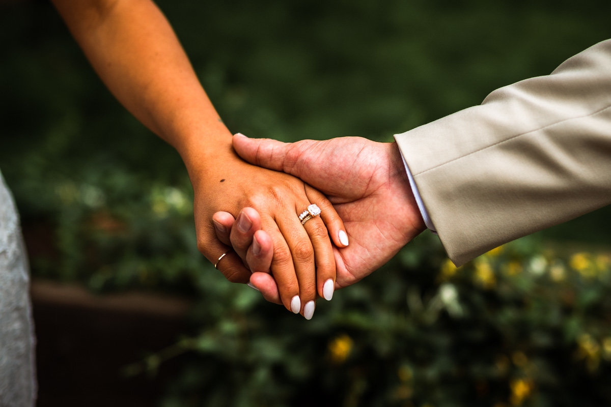 Detail image of wedding couple holding hands, showing the beautiful ring.