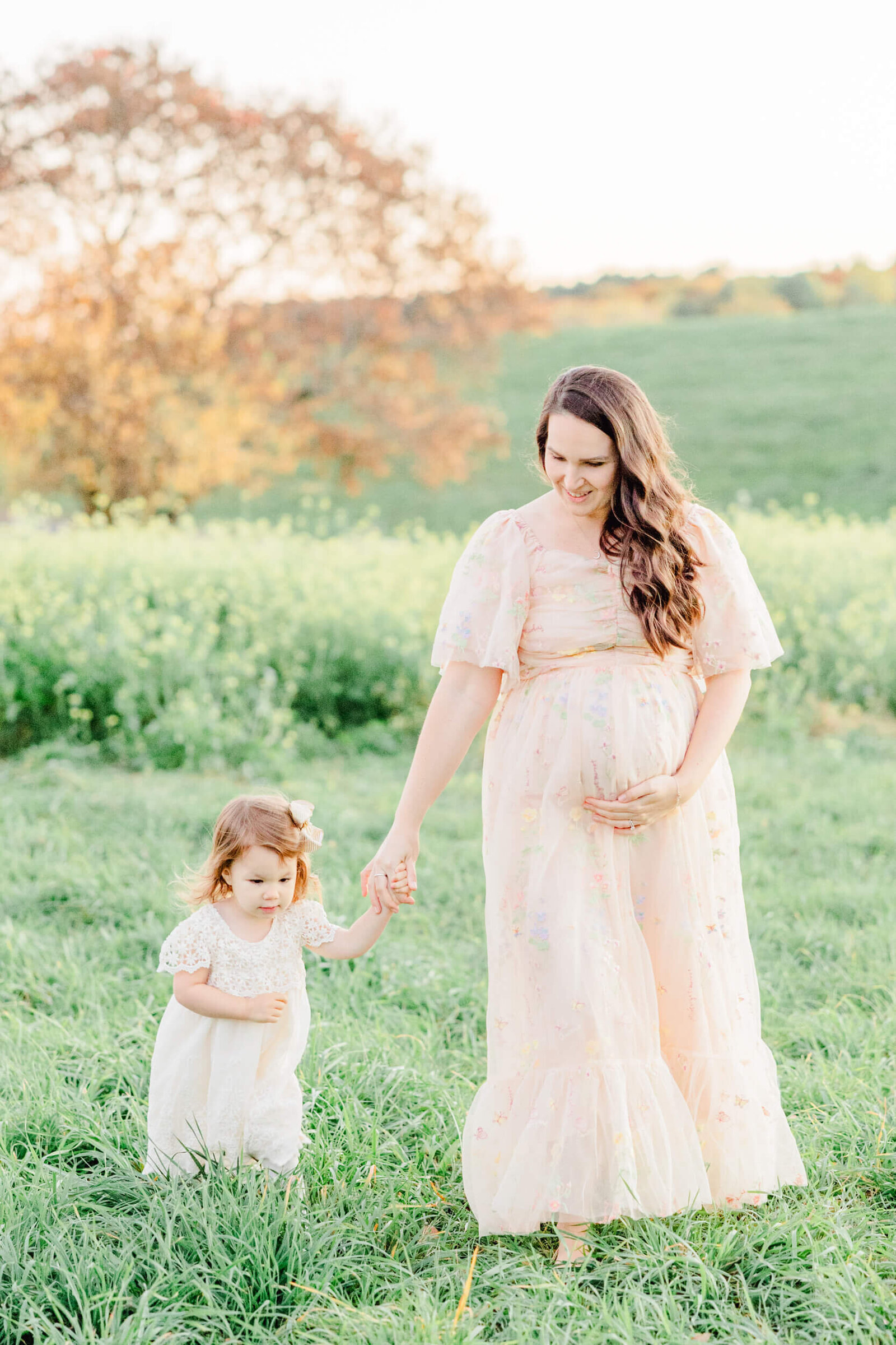 Pregnant mom walks holding hands with her daughter