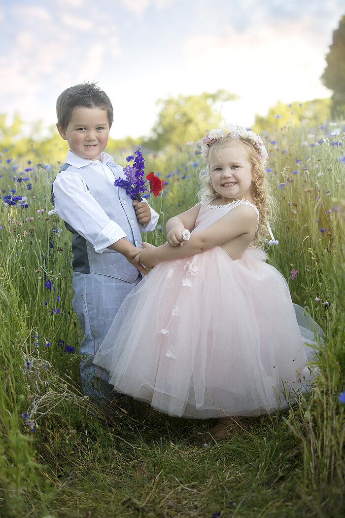 Boy and girl holding flowers in flower field.