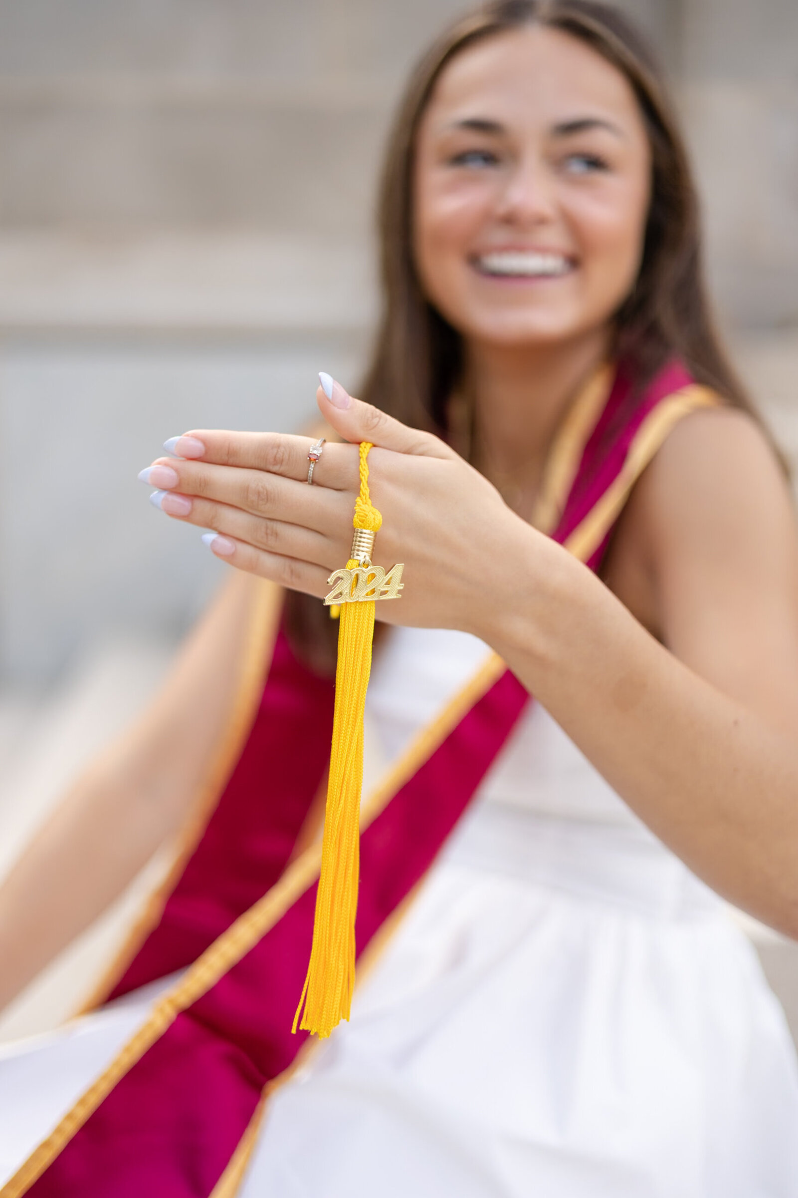 young women poses for cap and gown photo with tassel
