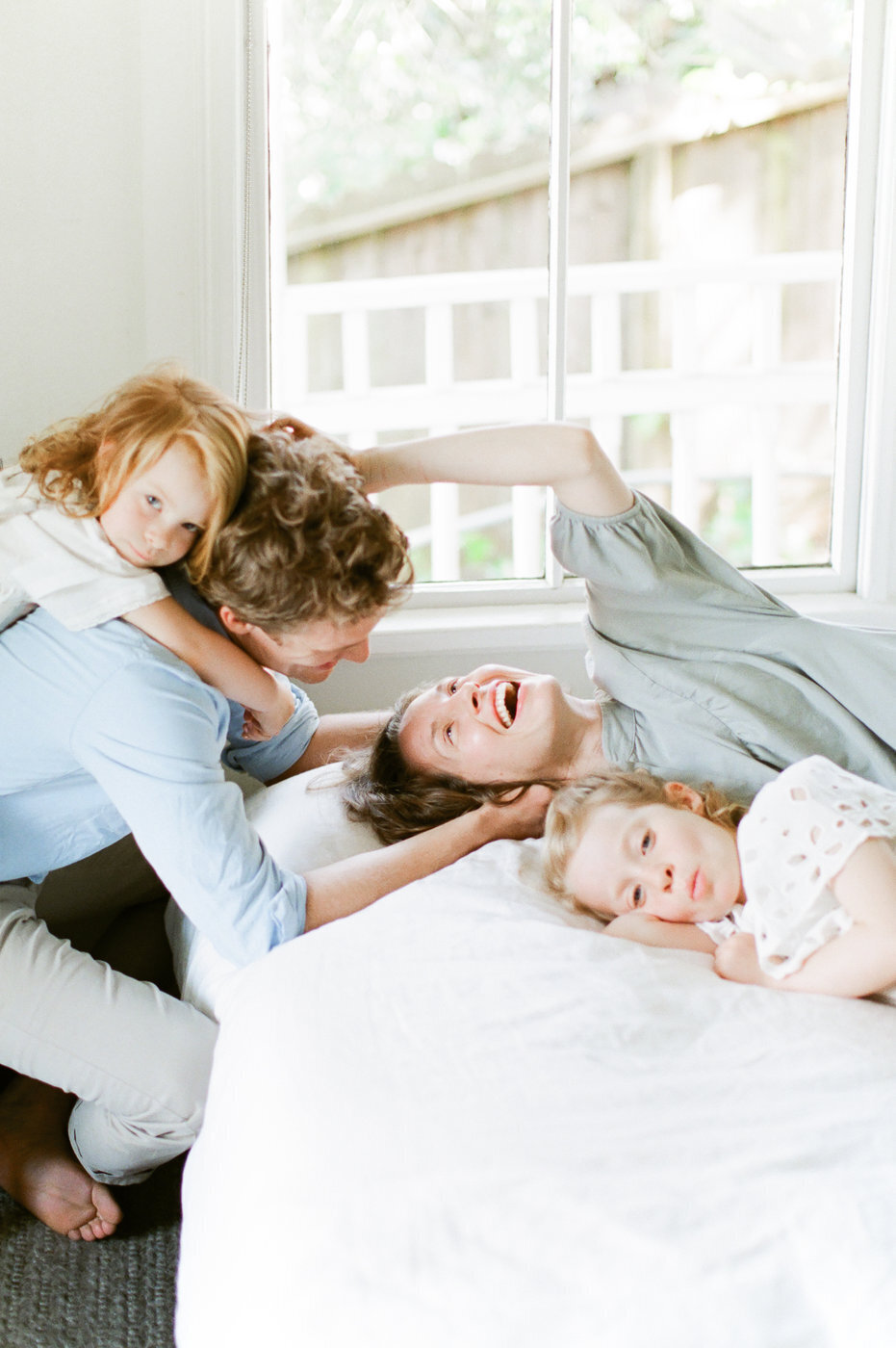 family snuggles on bed by Orlando family photographer